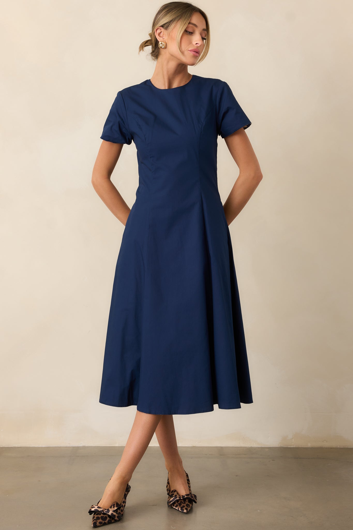Front view of short-sleeve midi dress showing Prosperina Navy Mod Blossom floral print and solid navy fabric, with pockets and flowy skirt.