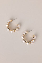 Top view of these pearl hoop earrings that feature gold hardware, six hemisphere pearls along the hoop, and a secure post backing.