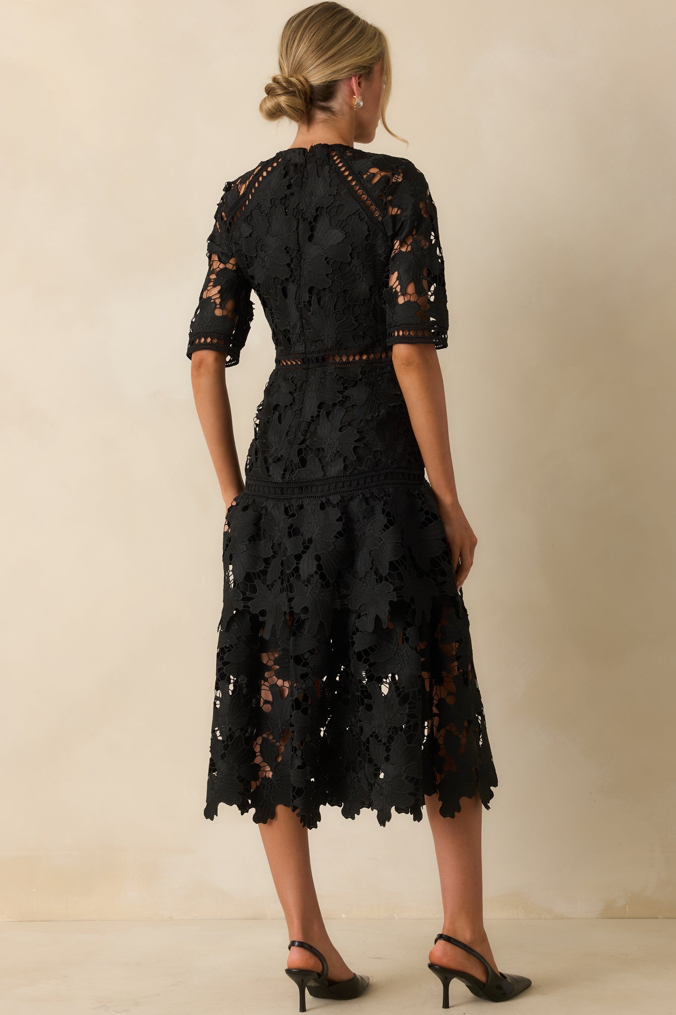 Rear view of the black lace dress with hidden zipper and tiered skirt finish.