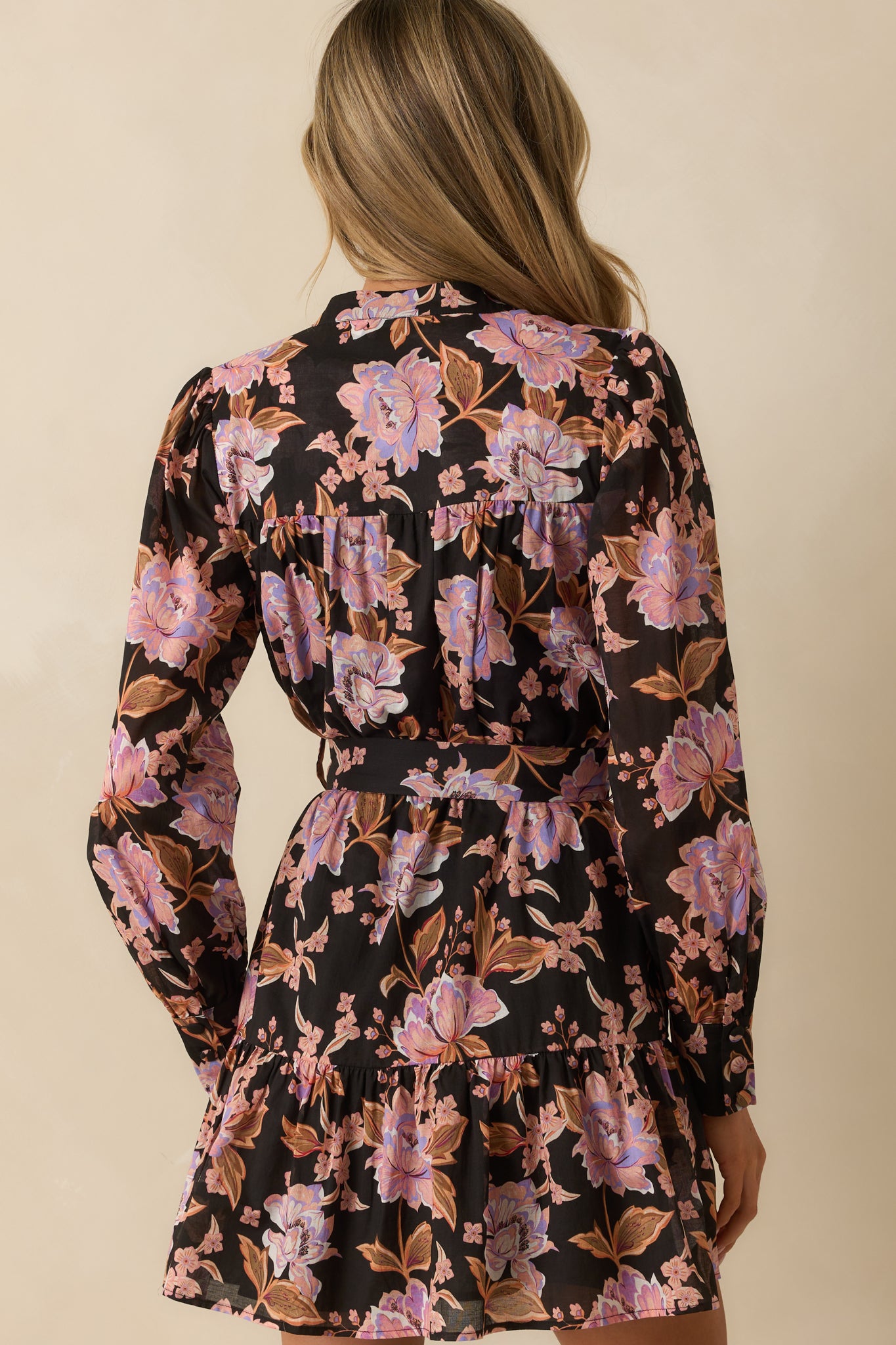 Rear view of the black mini dress with pink floral print and cinched waistband.
