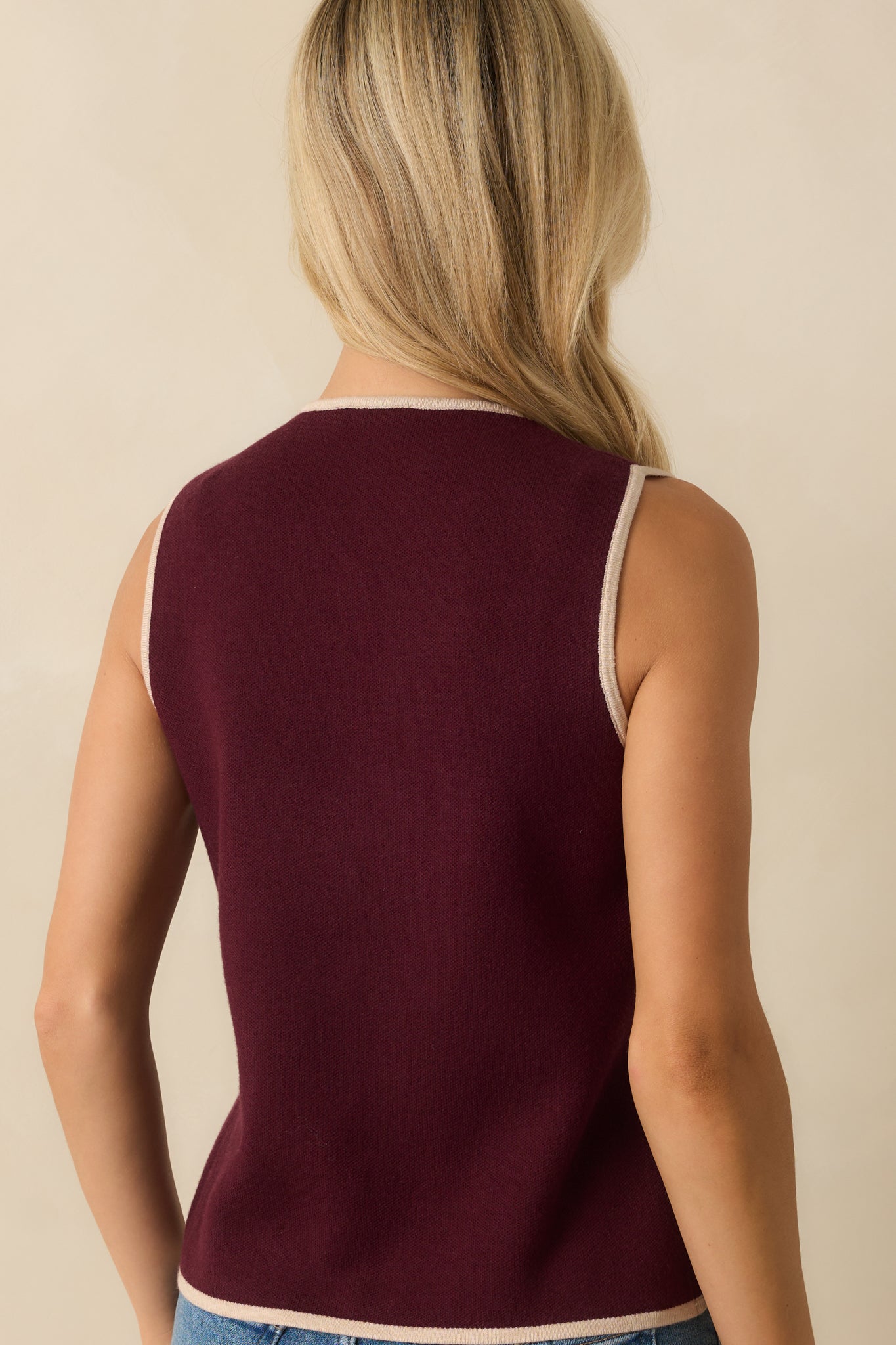 Rear view of the burgundy sweater vest with smooth knit fabric and ivory edging.