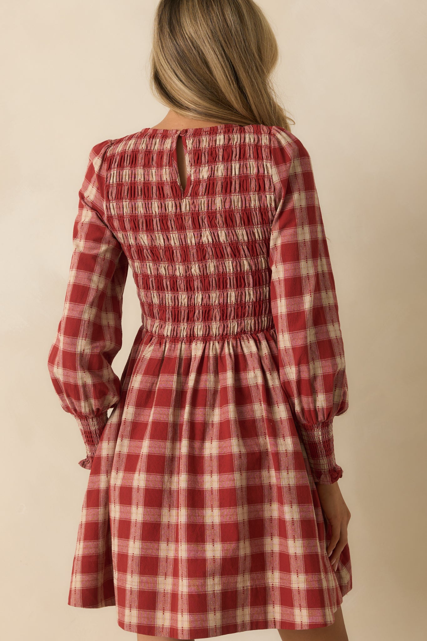 Rear view of the gingham mini dress with keyhole button closure and smocked bodice.