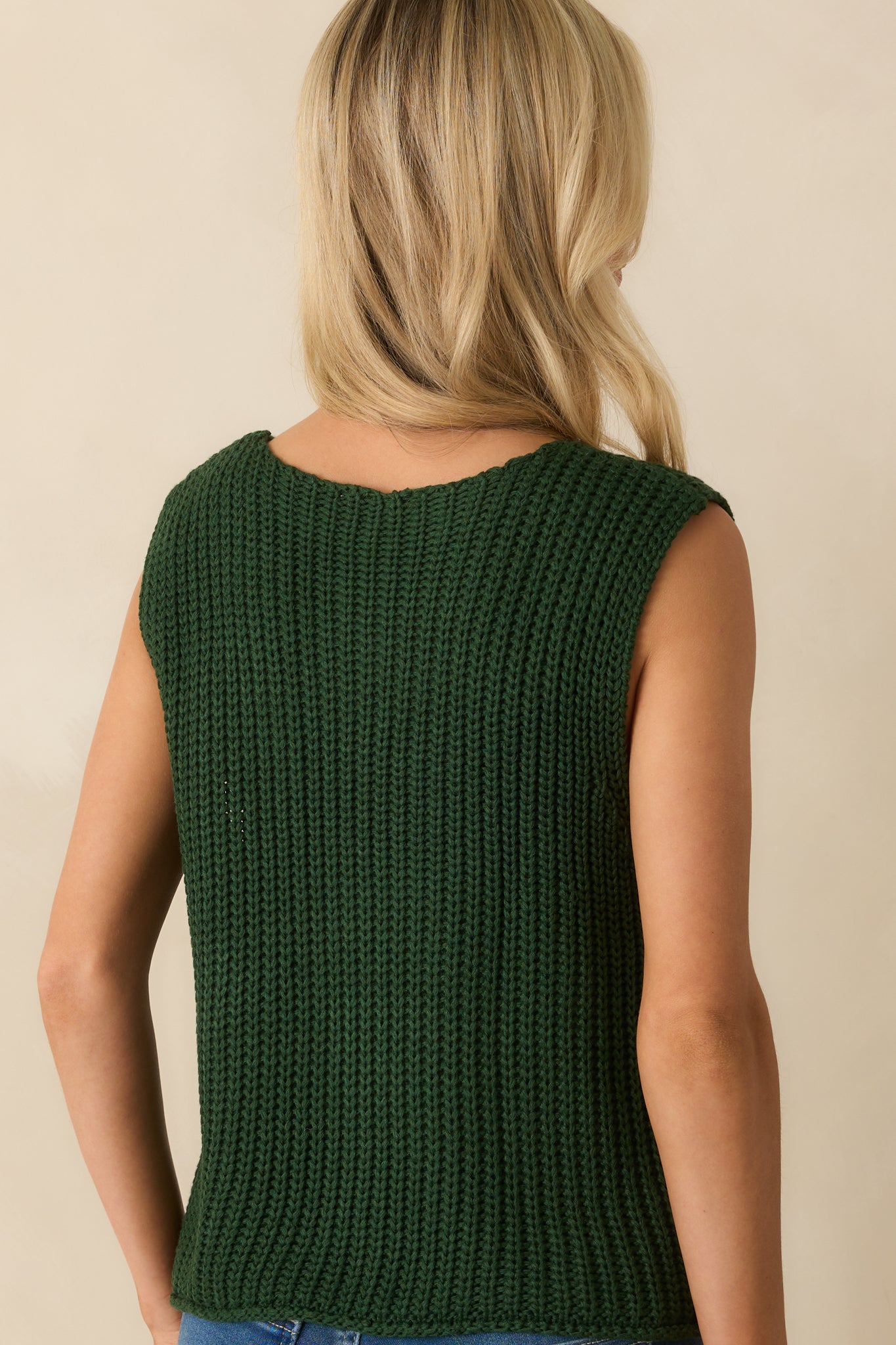 Rear view of the hunter green sweater vest with a straight hemline and sleeveless design.