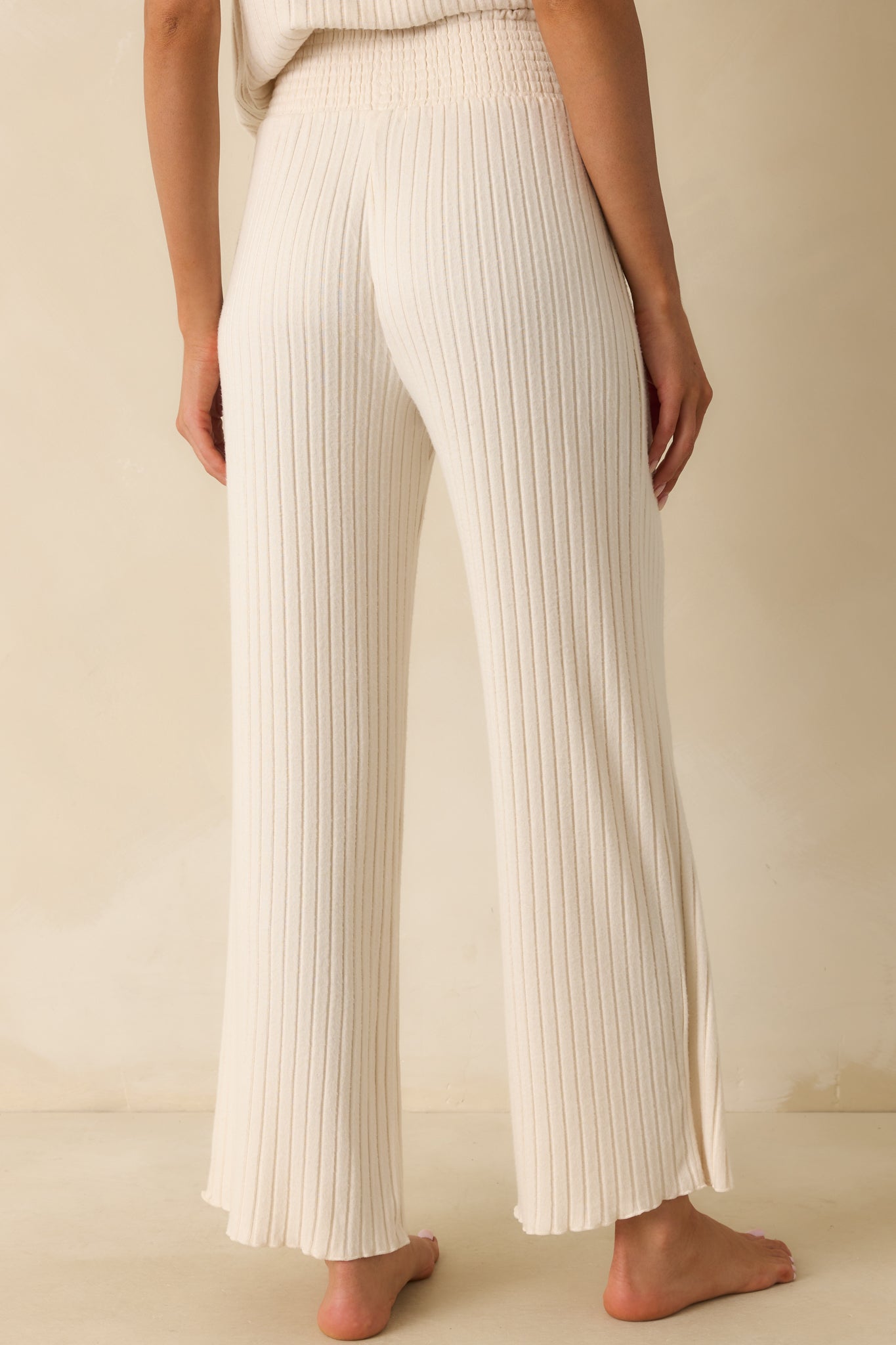 Rear view of the ivory ribbed pants with a wide leg silhouette and comfortable drape