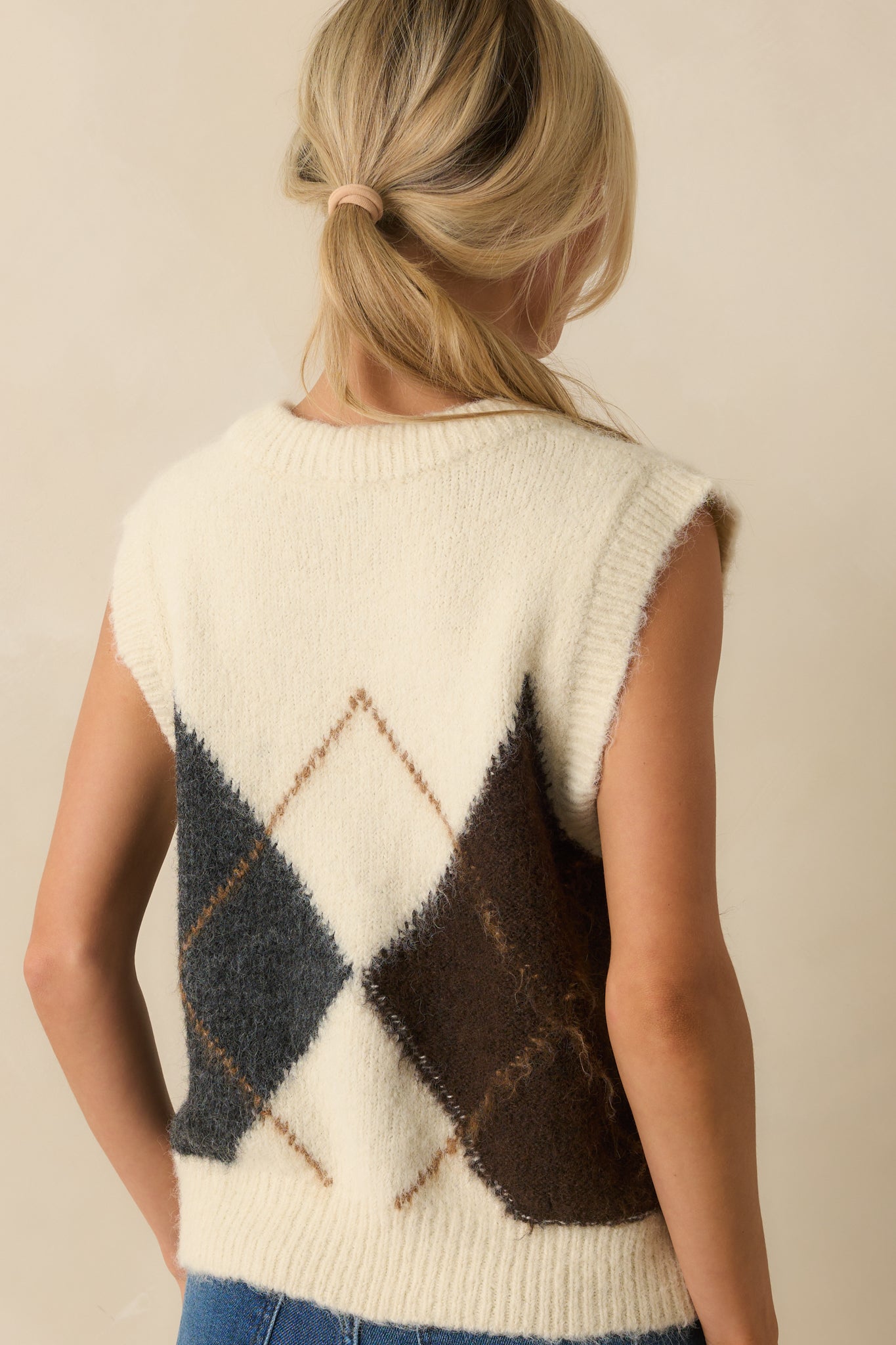 Rear view of the ivory sweater vest with sleeveless design and ribbed hem.