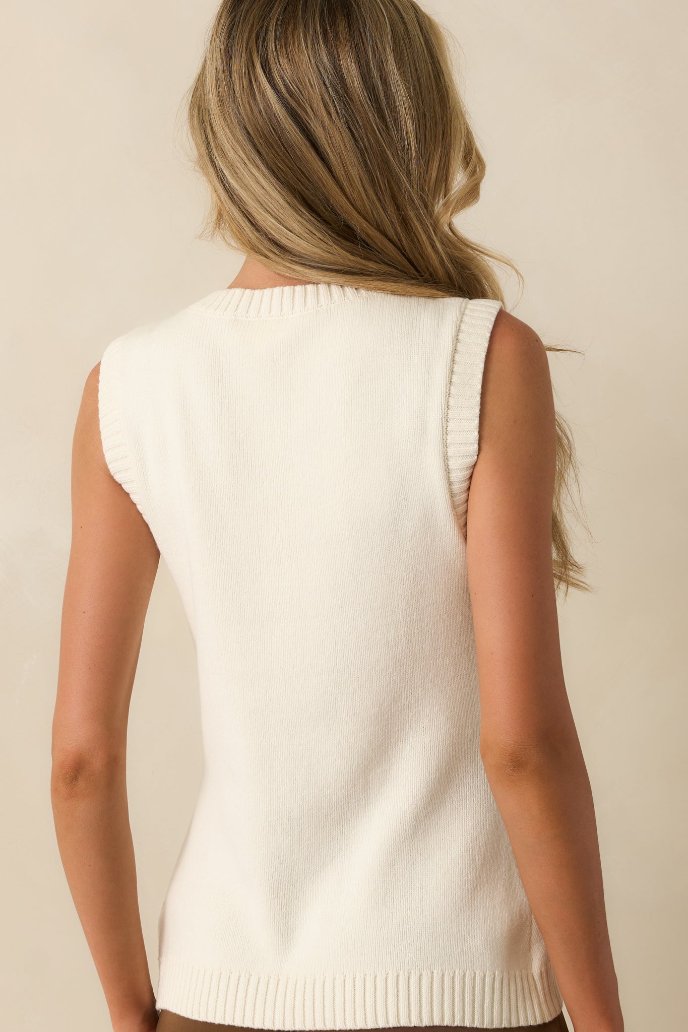 Rear view of the ivory sweater vest with a straight hem and smooth knit fabric.