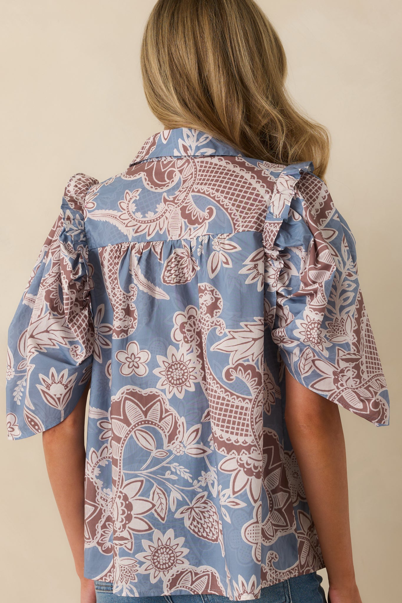 Rear view of paisley floral blouse featuring puff sleeves and relaxed silhouette.