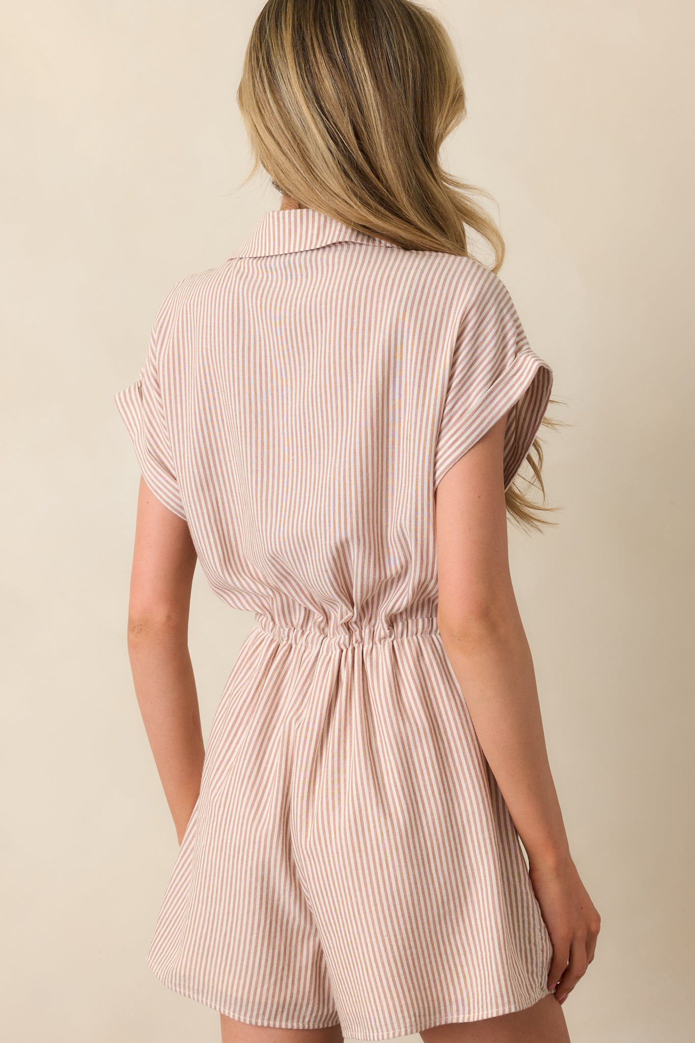 Rear view of the romper showing the simple back design, elasticized waist shaping, and folded sleeve cuffs.