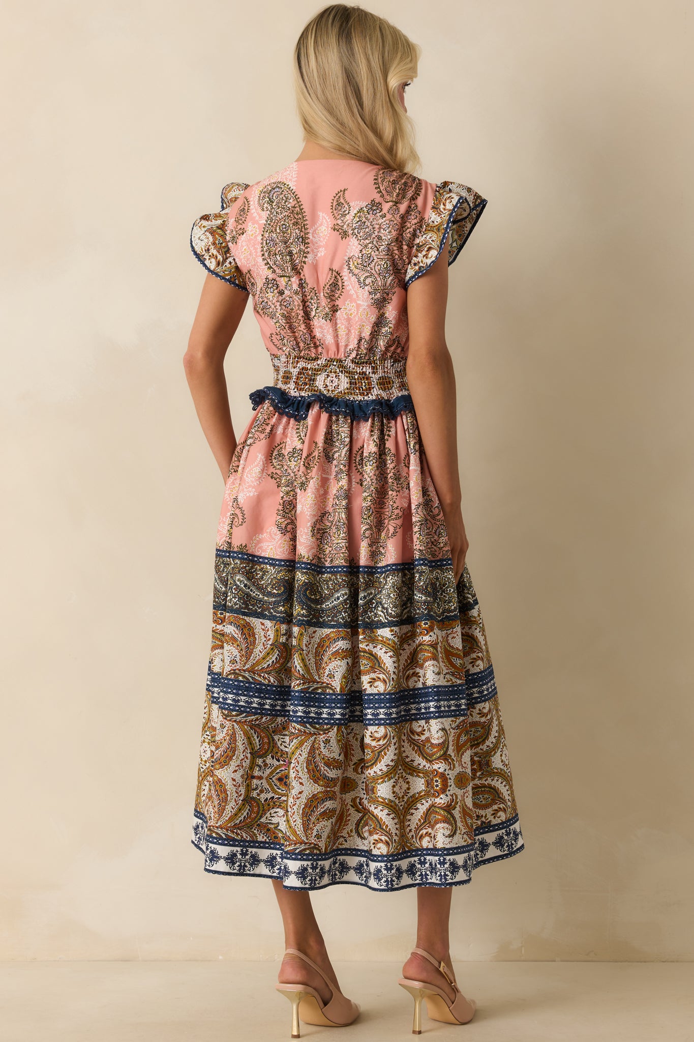 Rear view of the rose pink midi dress with flutter sleeves, smocked waistband, and full skirt.