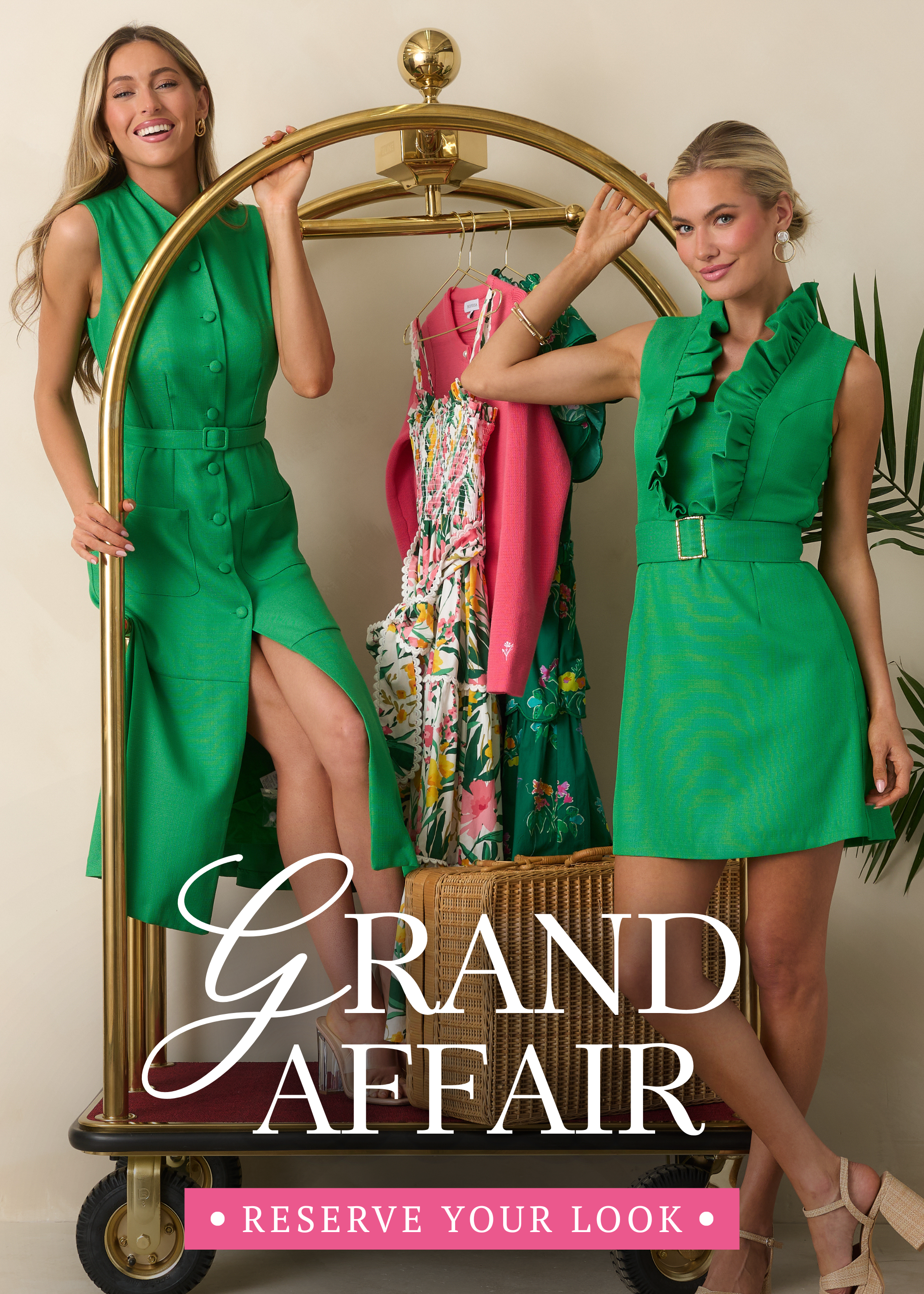 Two models wearing vibrant green dresses pose on a gold luggage cart with colorful floral dresses and pink knitwear for the Red Dress Grand Affair collection. This banner leads to shop the Grand Affair collection featuring polished spring dresses and elevated occasion styles.