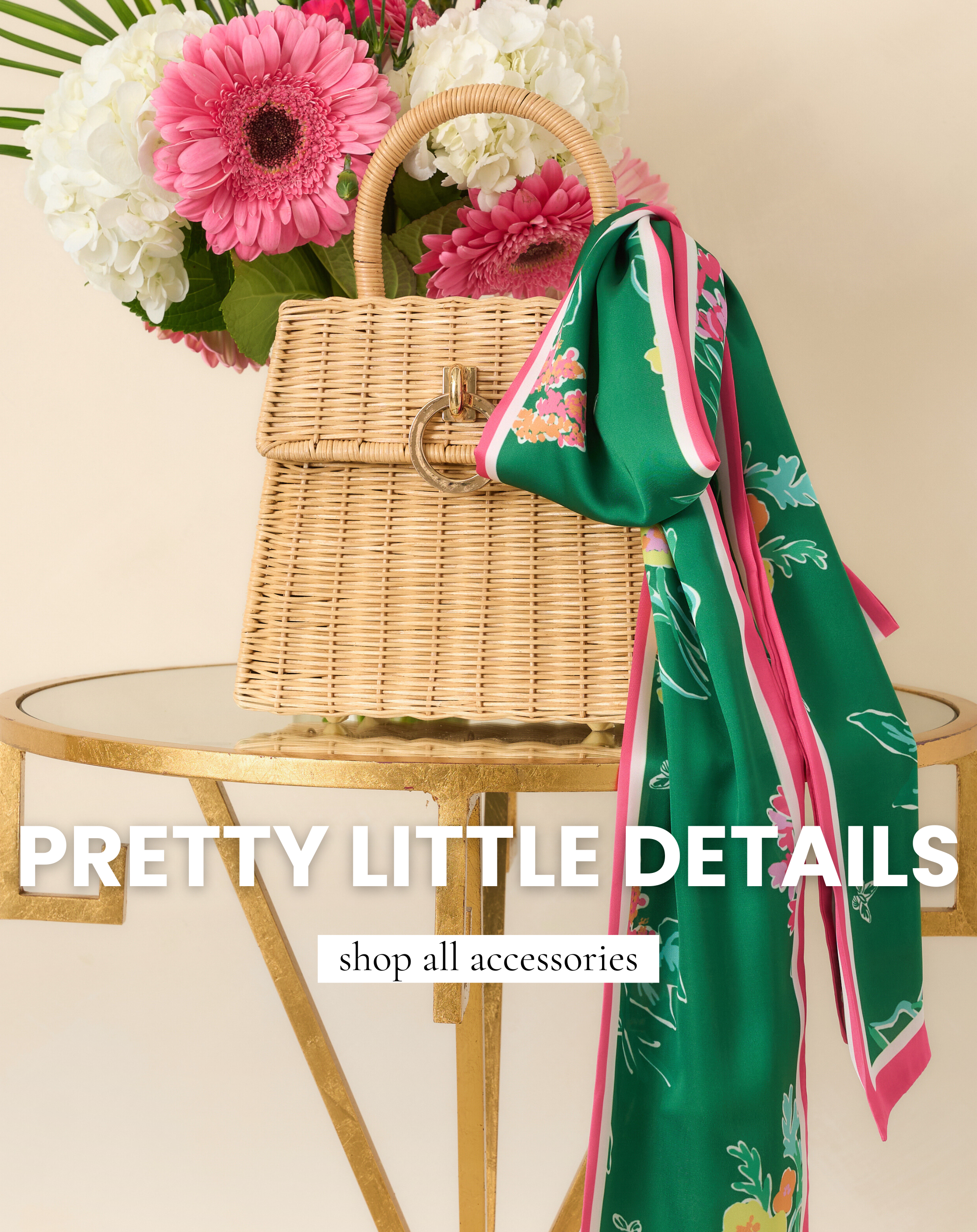 A woven rattan handbag styled with a vibrant green floral scarf sits beside pink gerbera daisies and white hydrangeas on a gold table. This image leads to shop all accessories from Red Dress.