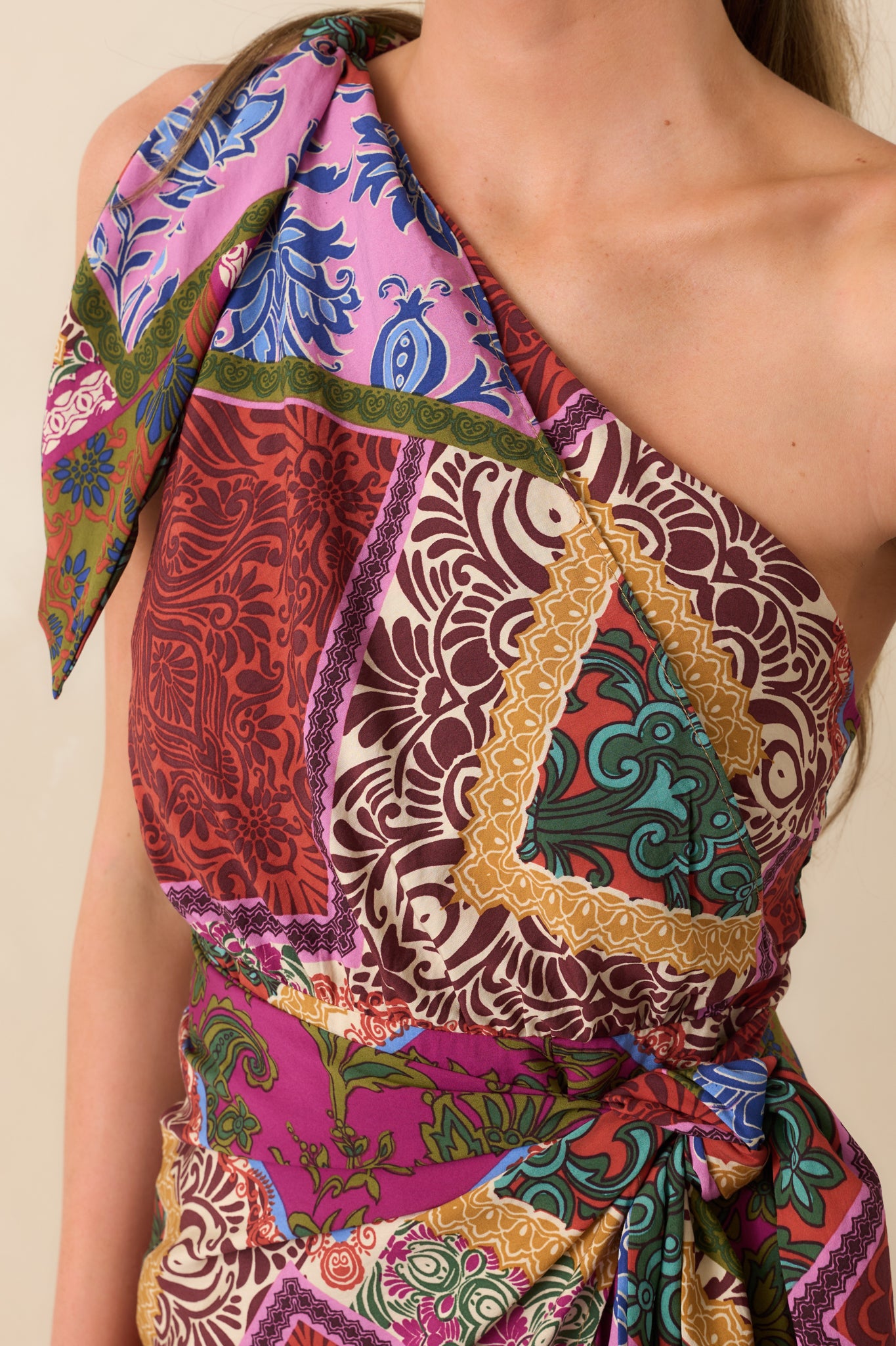 Close-up of fabric showing multicolor patchwork print and knot detail at one shoulder.