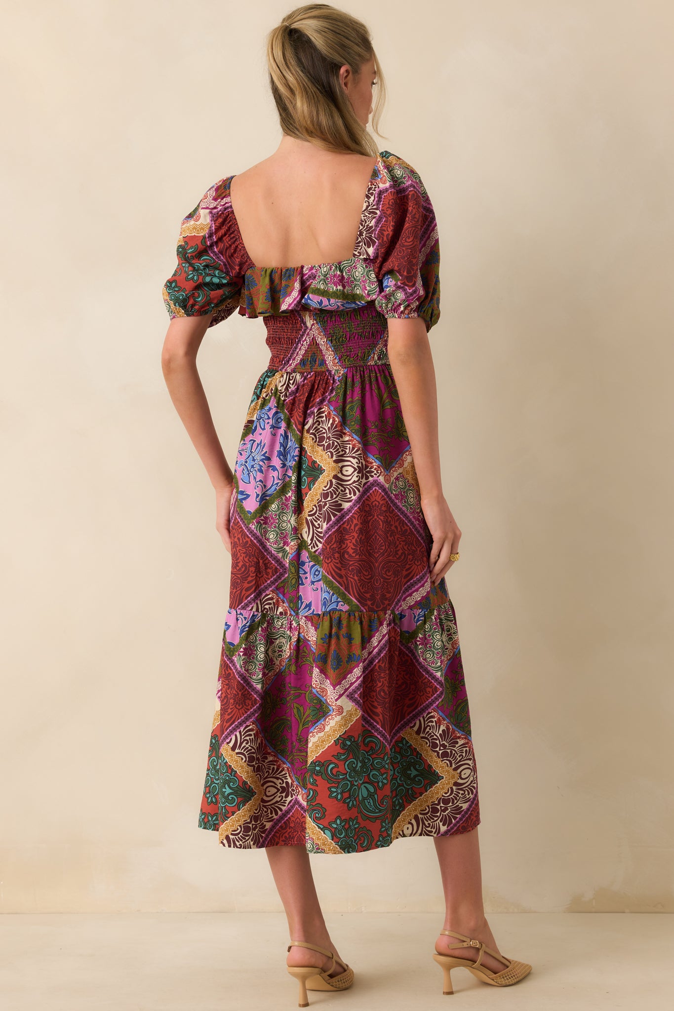 Back view of red patchwork midi dress showing short puff sleeves with elastic cuffs and tiered skirt.