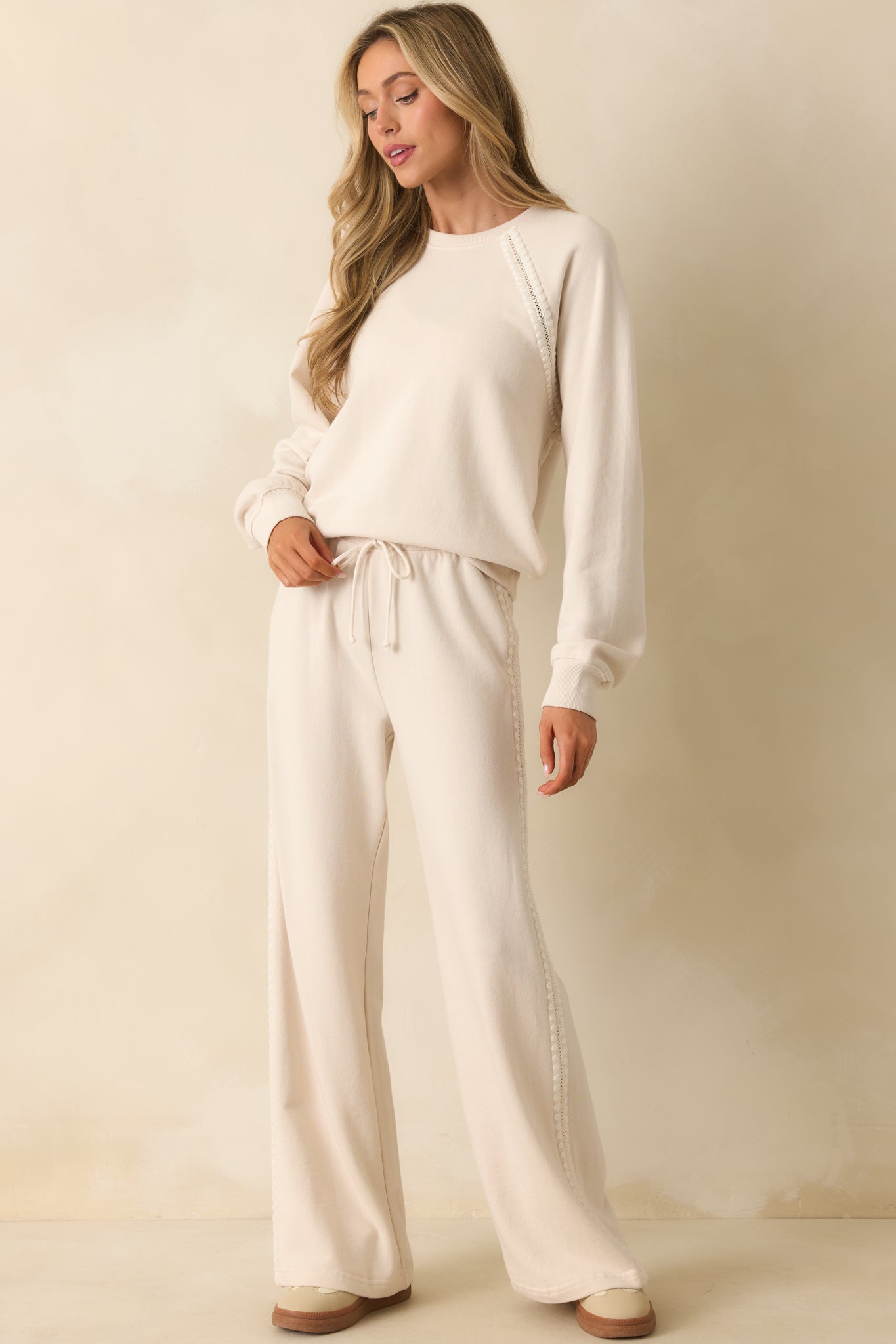 Relaxed ivory pants featuring crochet trim details running down the sides.