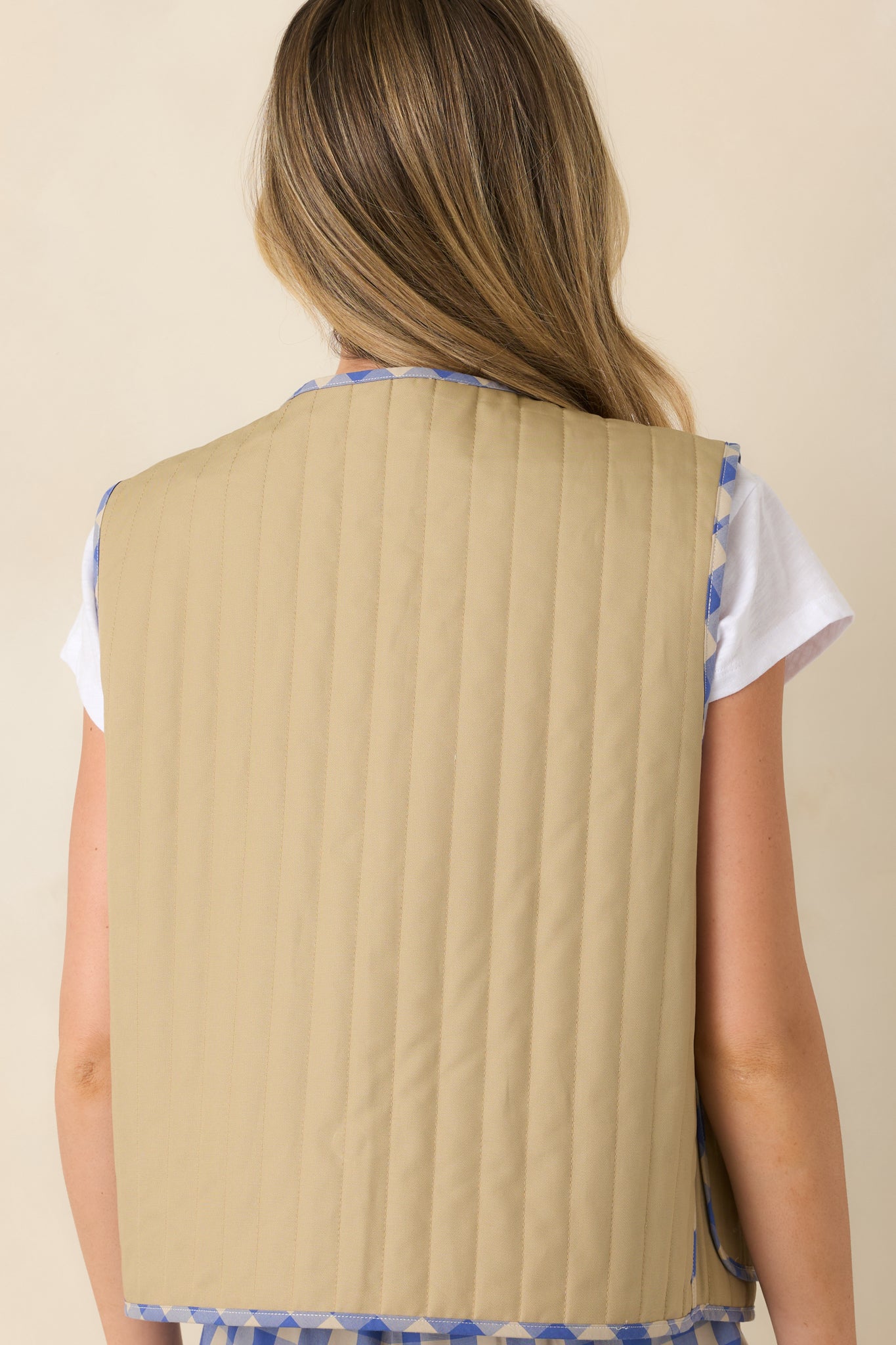 Back view of the reversible quilted vest featuring the solid khaki side with vertical quilted stitching.