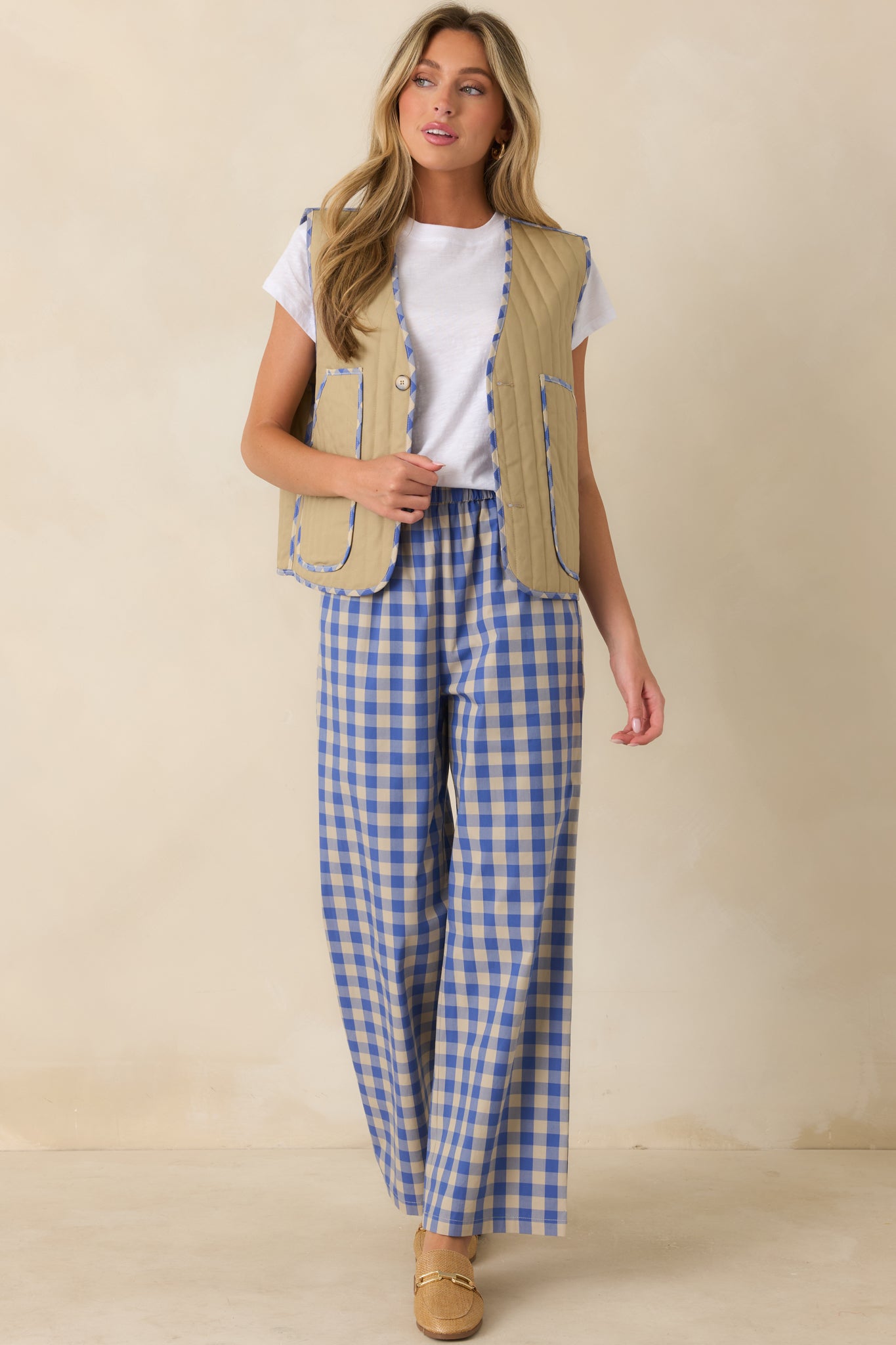 Model wearing the reversible khaki quilted vest over a white tee with matching blue gingham wide leg pants.