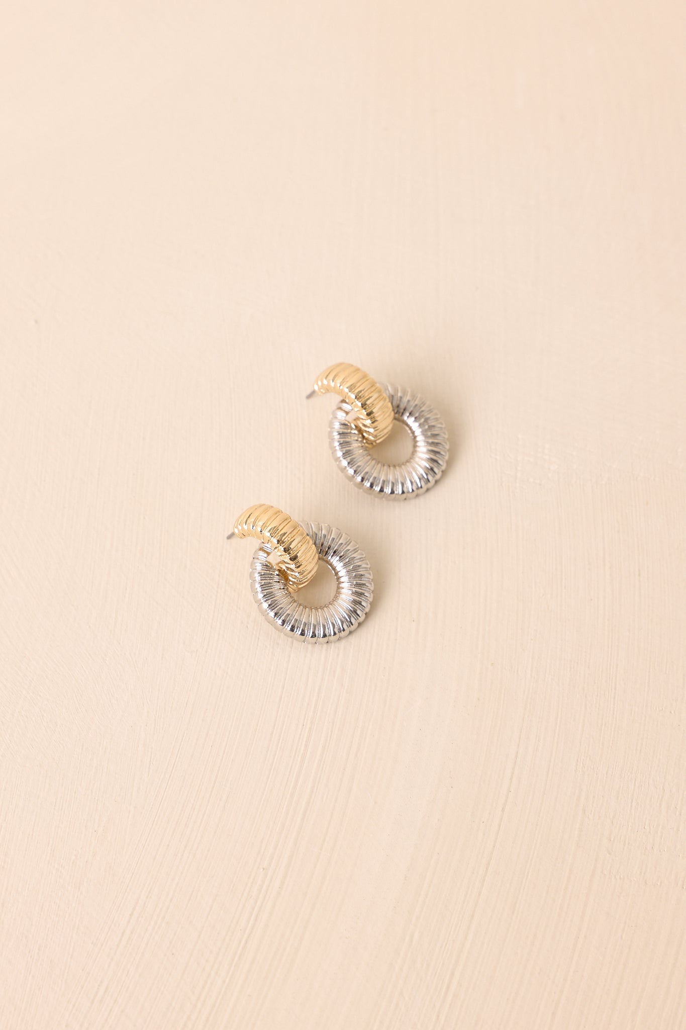 A detailed shot of the ribbed silver hoop earrings with a central gold-tone half-hoop link and polished finish.