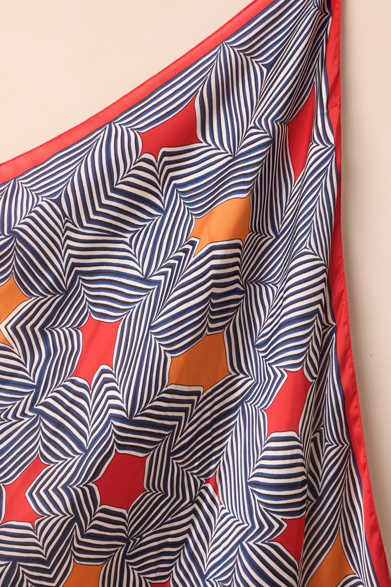 Close-up of the scarf showing the detailed geometric stripe pattern and the smooth, shiny red border.