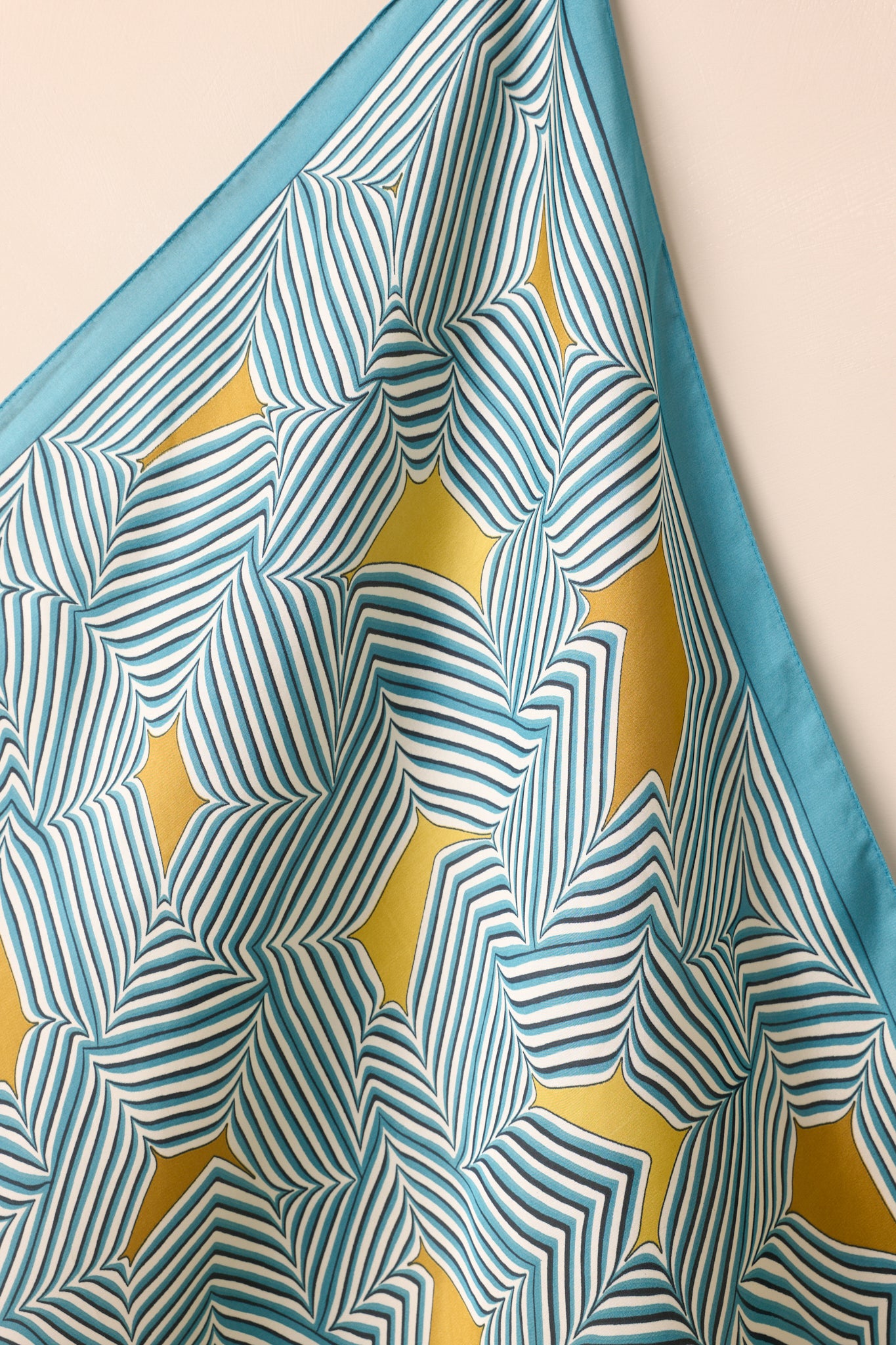 Close-up of the scarf’s corner, highlighting the satin sheen, golden yellow details, and crisp striped geometric print.