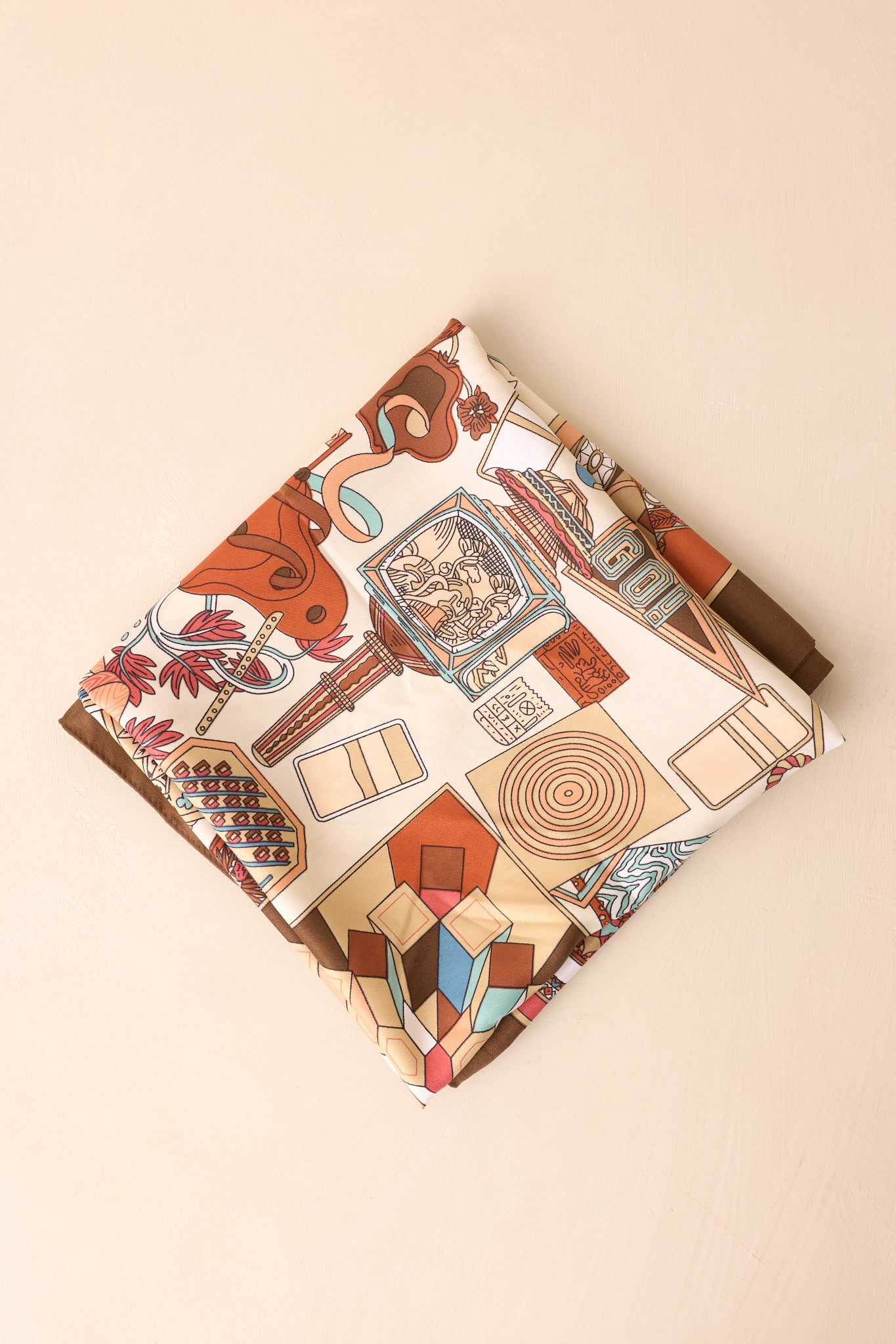 Scarf folded neatly into a small square, revealing overlapping brown multicolor prints and parts of the diverse motif patterns.