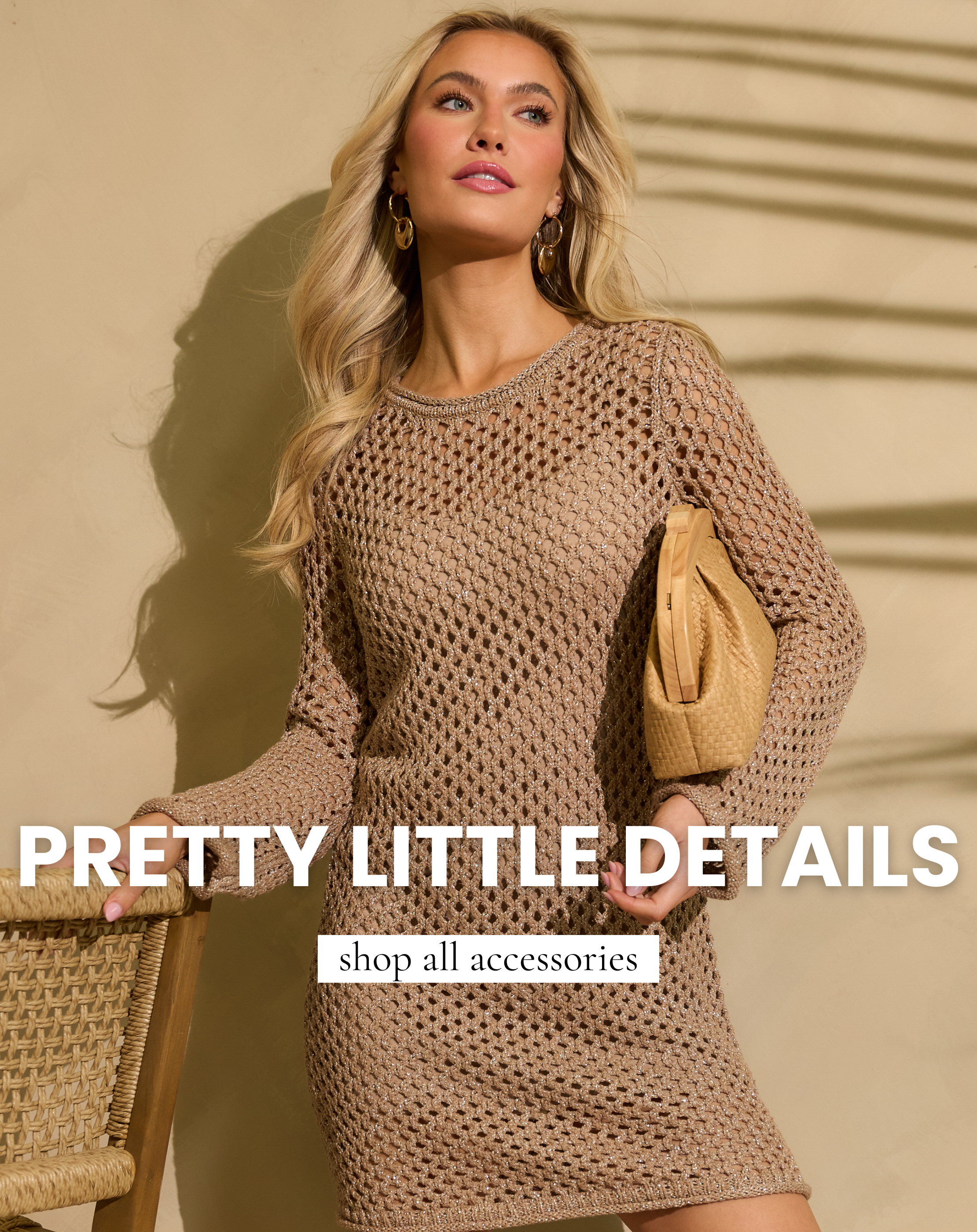 Model wearing a neutral open knit long sleeve mini dress with gold hoop earrings and holding a woven straw clutch handbag. The bag and earrings are featured in All Accessories Shop