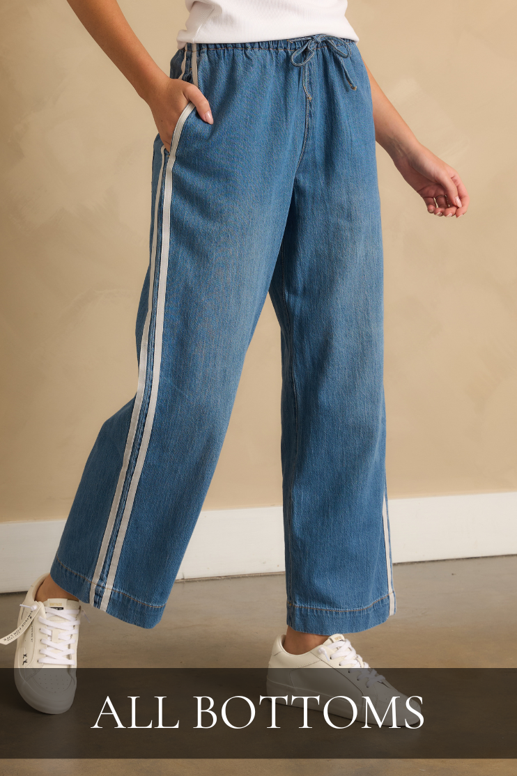 Shop all bottoms featuring light wash wide-leg denim pants with contrast side stripes paired with white sneakers.