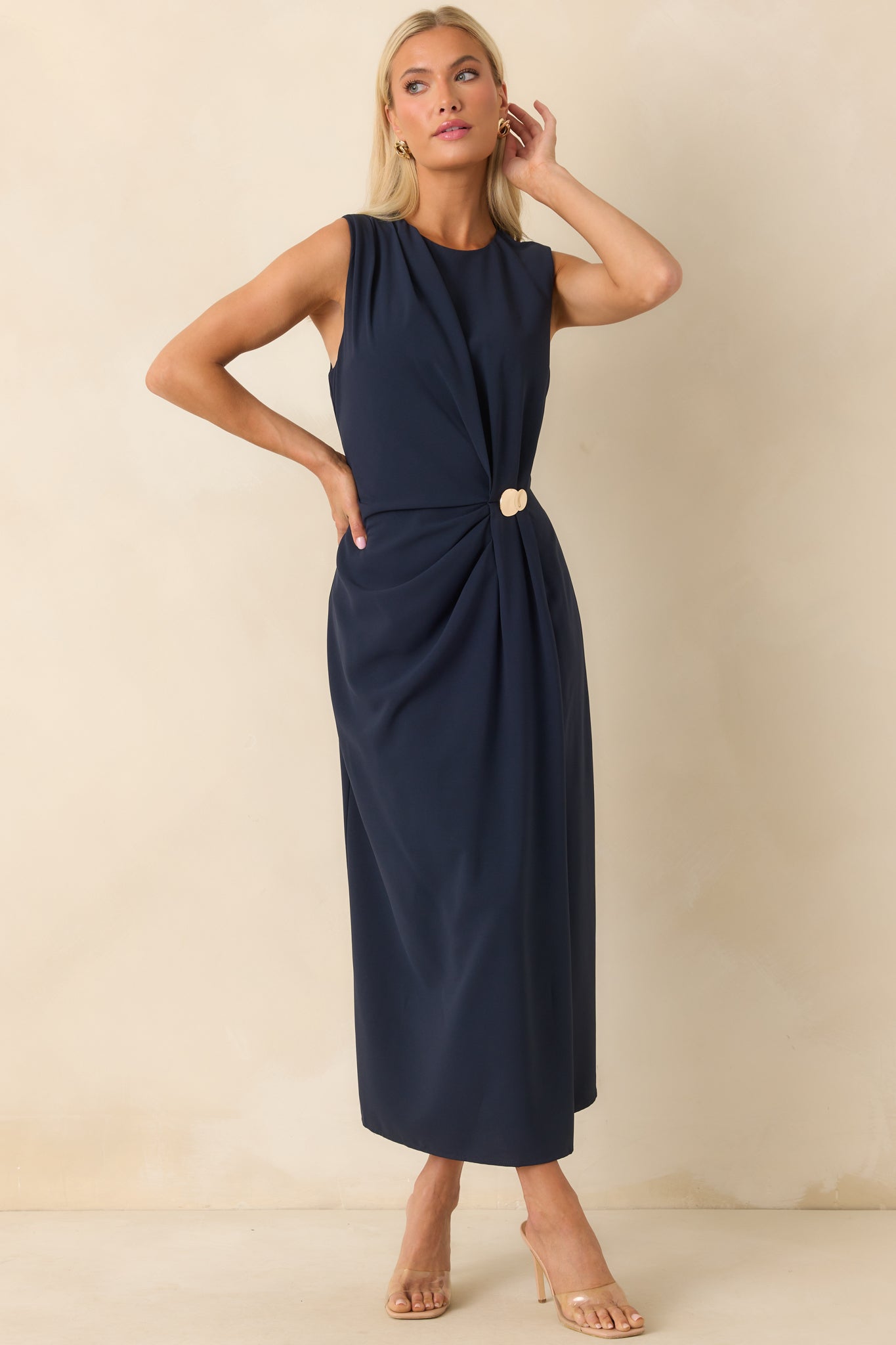 Full front view of the navy sleeveless dress with a round neckline and central gold accent sewn into the ruching