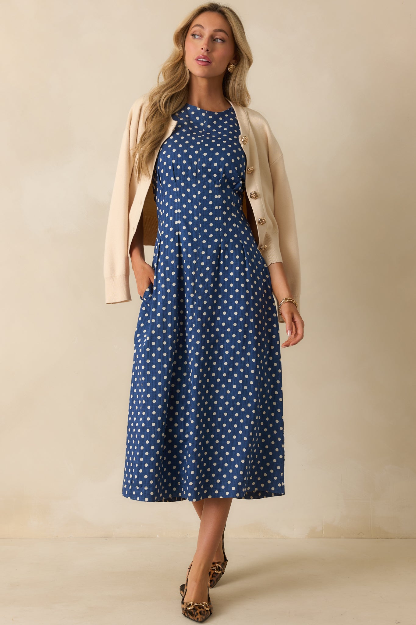 Sleeveless navy midi dress with white polka dots and a round neckline.