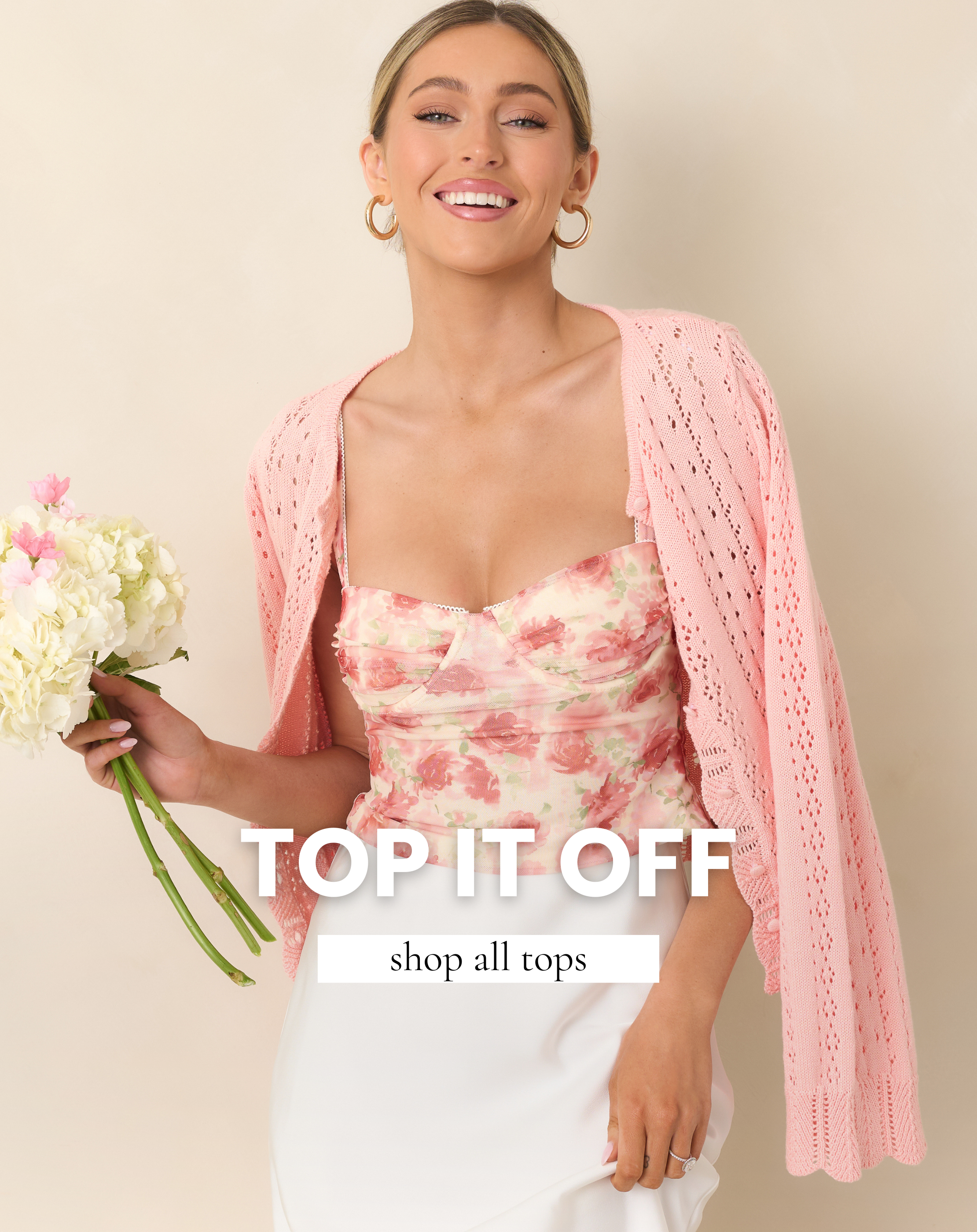 Model wearing a feminine pink floral bustier top styled with a soft pink knit cardigan and white skirt, showcasing a timeless and classic women’s top from our Color Cure collection. Shop all tops.