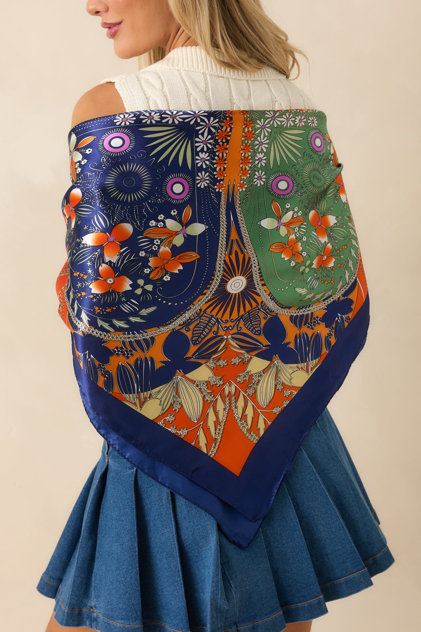 Rear view of the square orange scarf highlighting the multicolor floral print and contrasting border.
