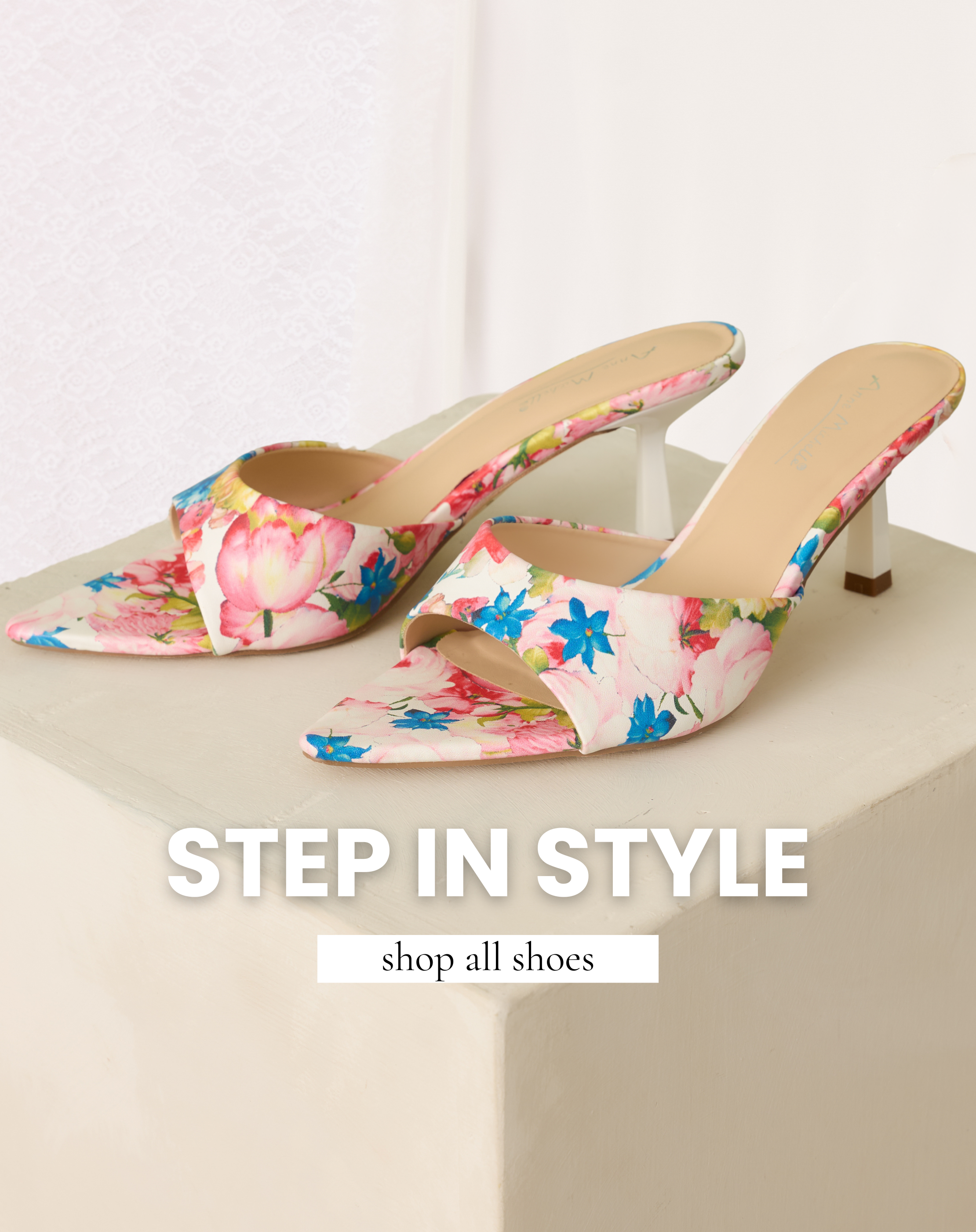 Pair of floral pointed-toe heeled mules displayed on a cream pedestal, promoting Red Dress shoe collection and linking to the Red Dress women’s shoe shop.