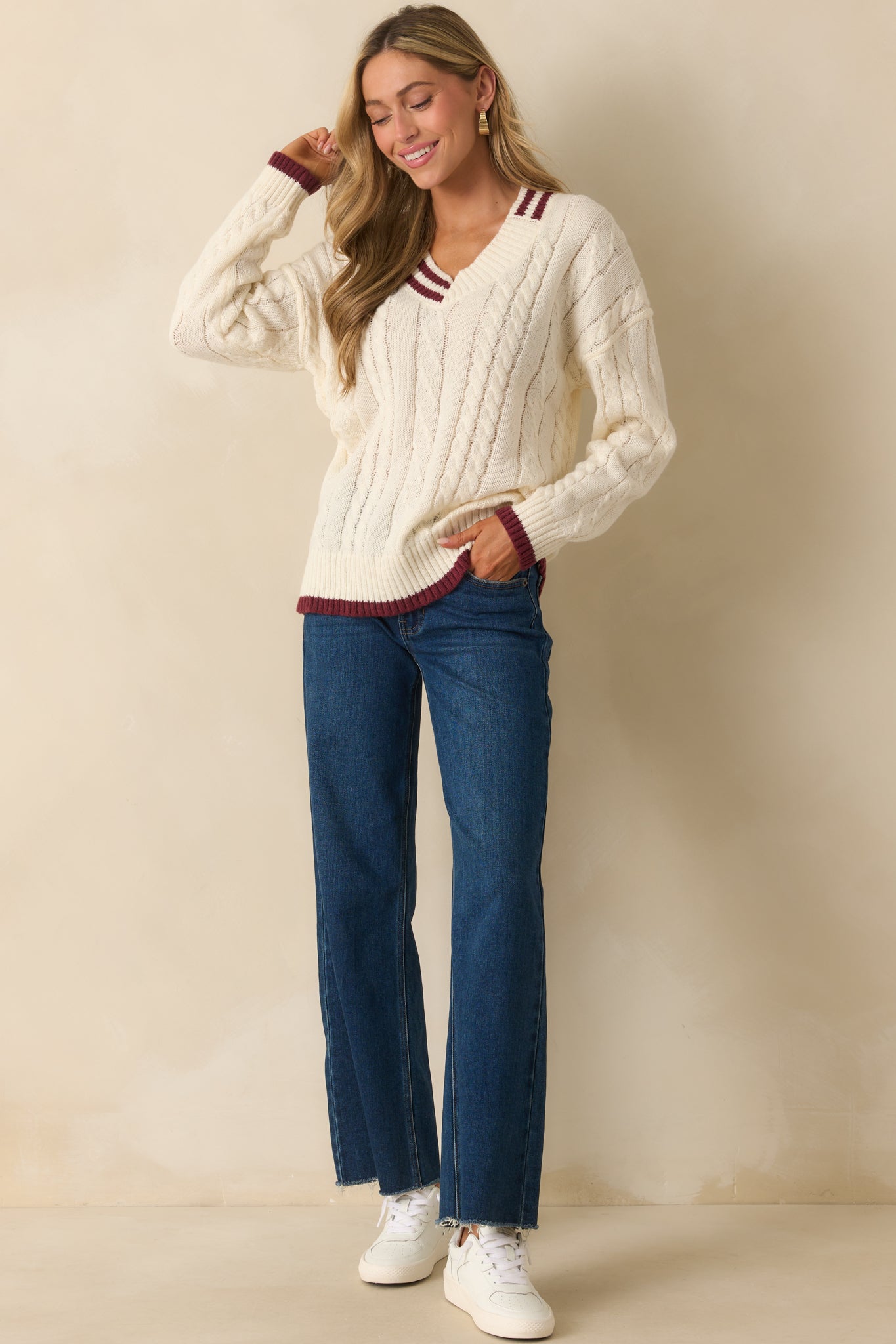 Sweater featuring a deep V-neck, long sleeves, and burgundy accents along edges.