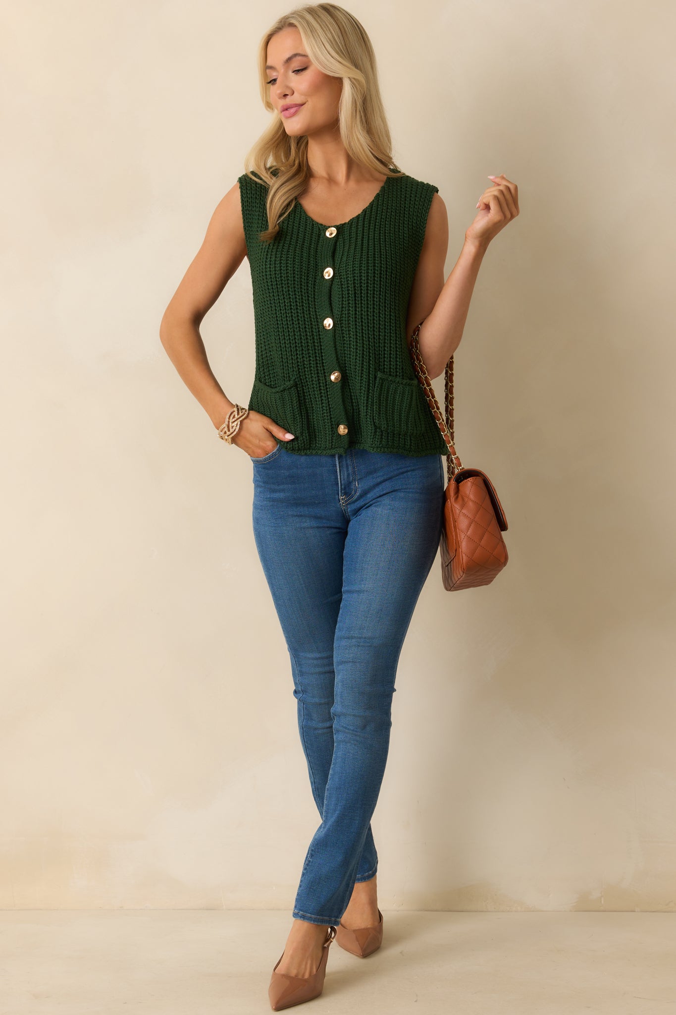 Sweater vest featuring a straight hemline, front patch pockets, and hammered gold button closure.