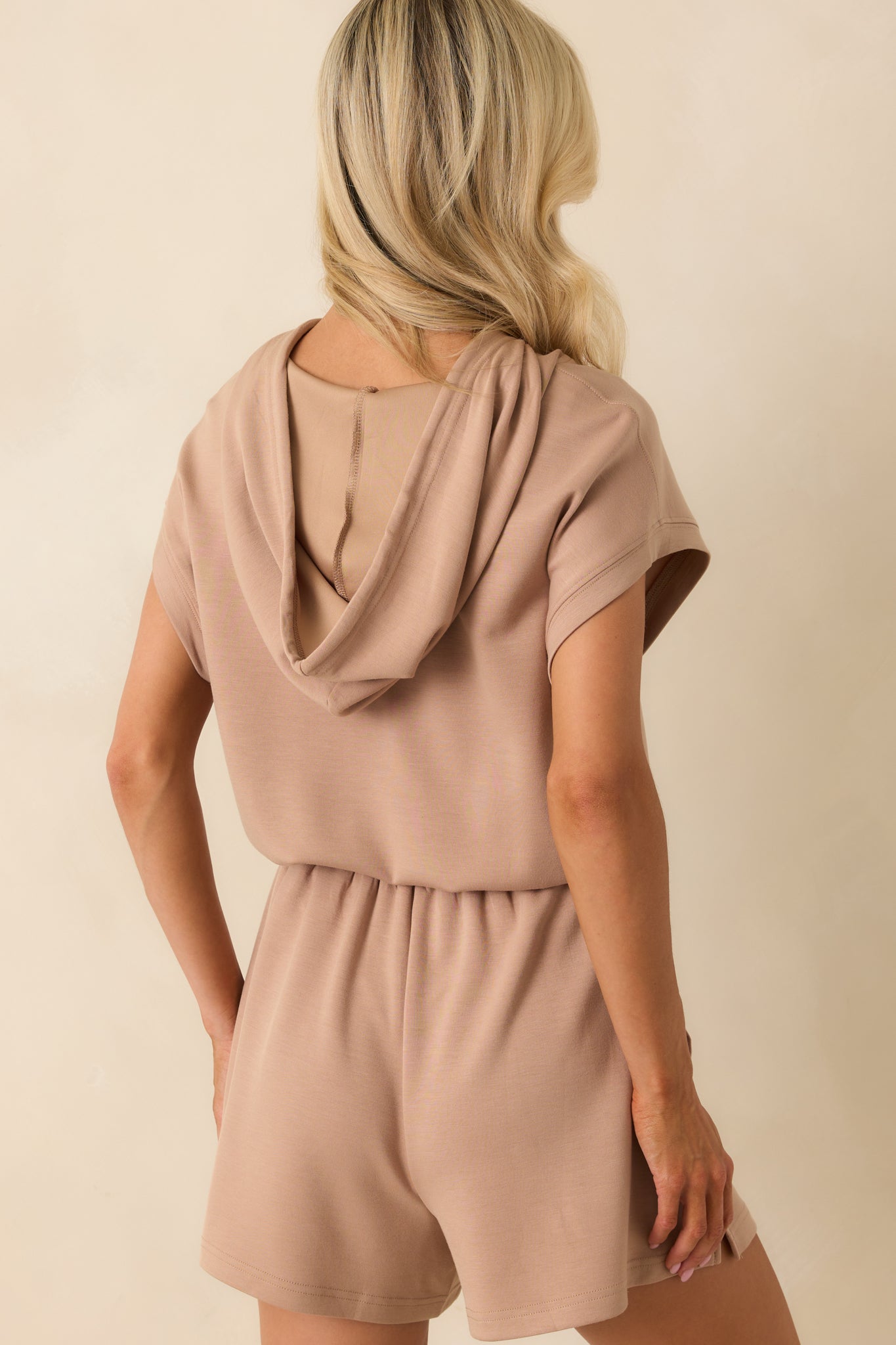 A back view of the romper showing the full hood, relaxed fit, and defined waistband from behind.