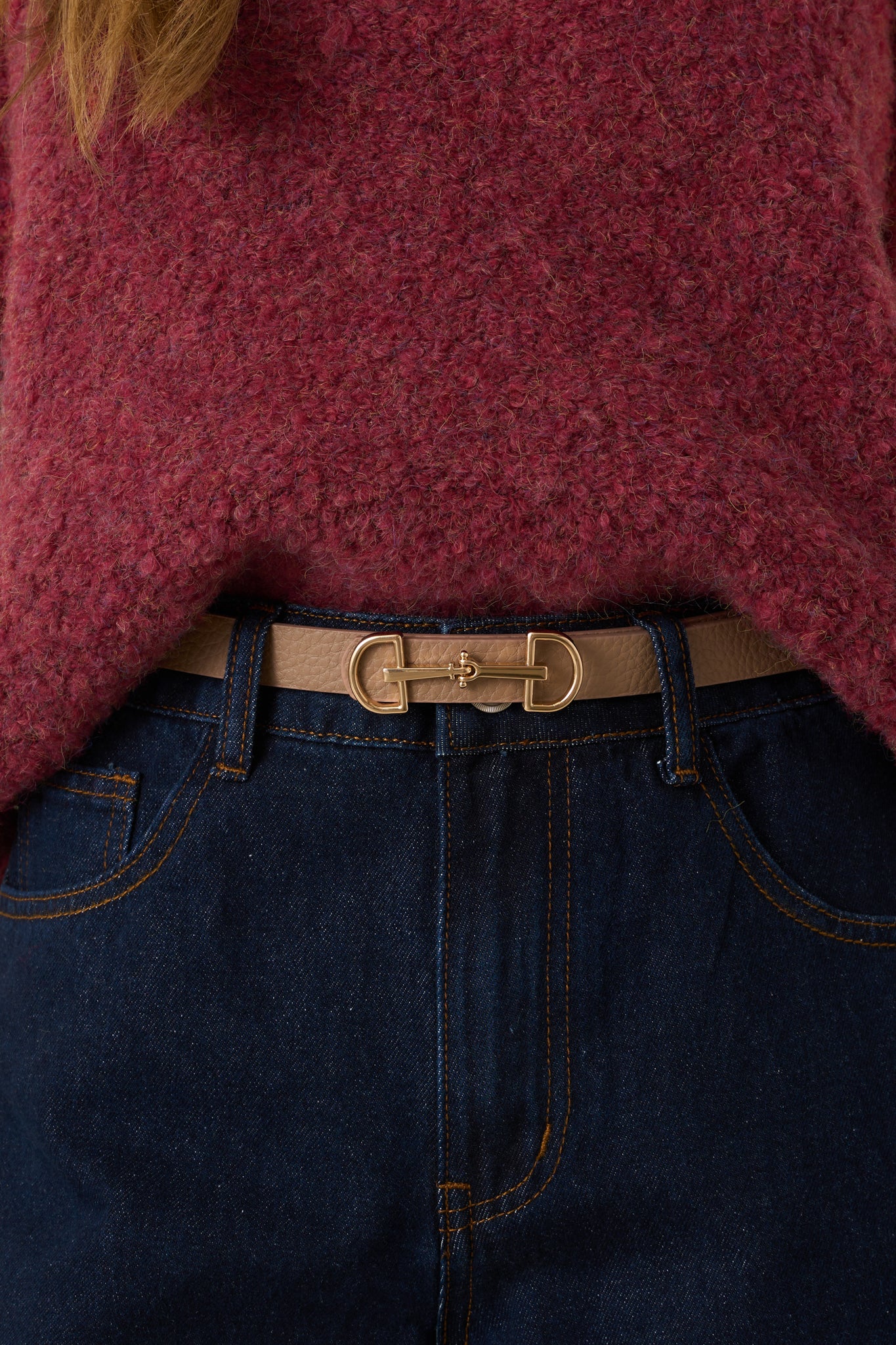 A cropped view of the tan belt wrapped at the waist, showing the textured faux leather material.