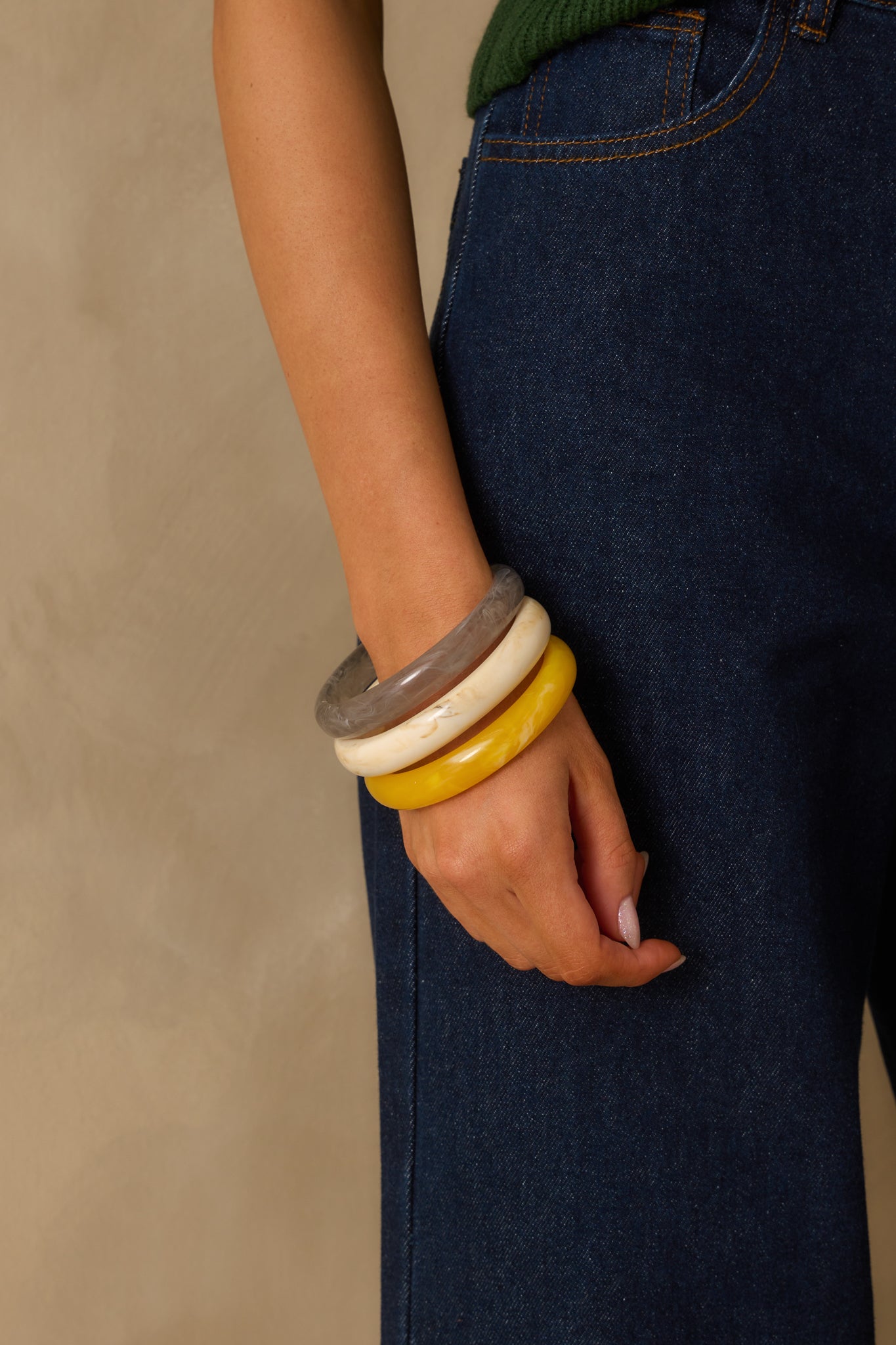 Cropped view of the three-piece bangle set stacked together, showing the contrast between the yellow, ivory, and grey marbled finishes.