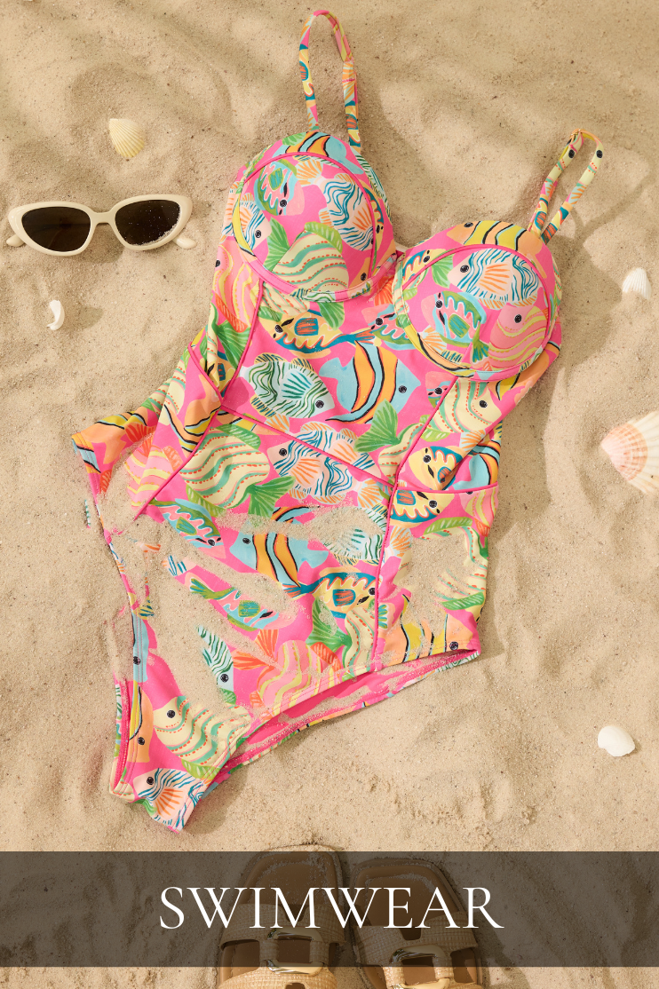 Colorful tropical print one-piece swimsuit styled on sand with sunglasses featured in the Red Dress Swimwear collection.