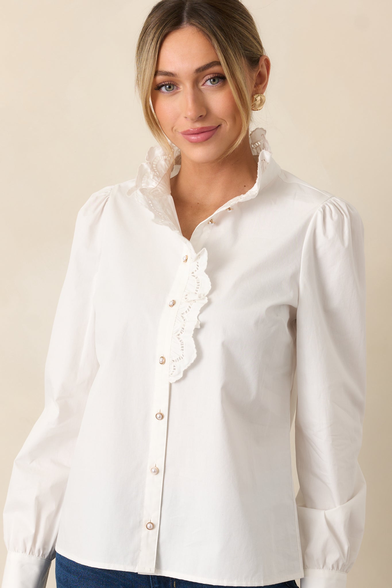 Cropped front view of white blouse focusing on lace trim and pearl button cuffs.