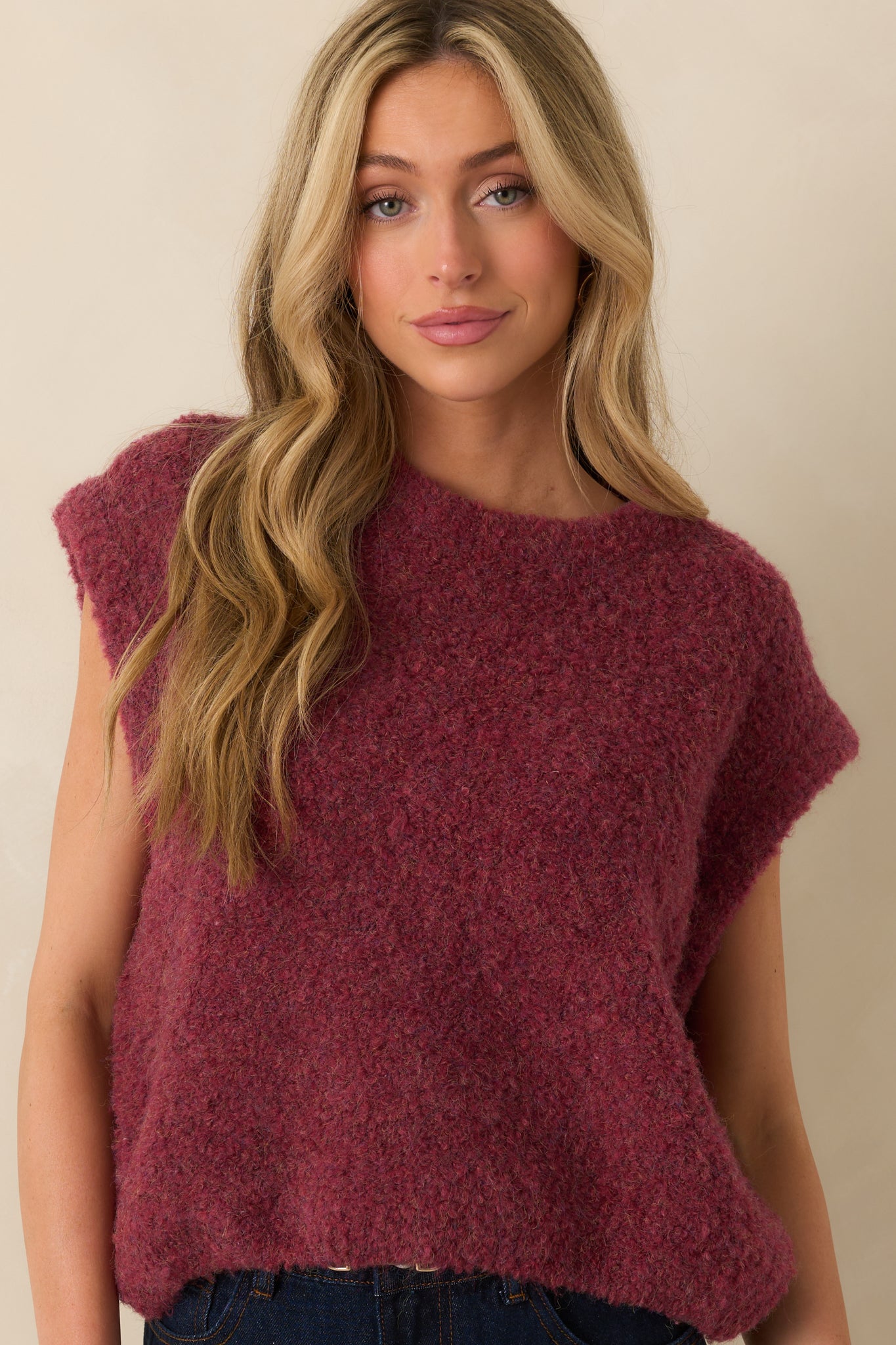 Close crop showing the hem and fabric texture of the wine-colored sweater vest.