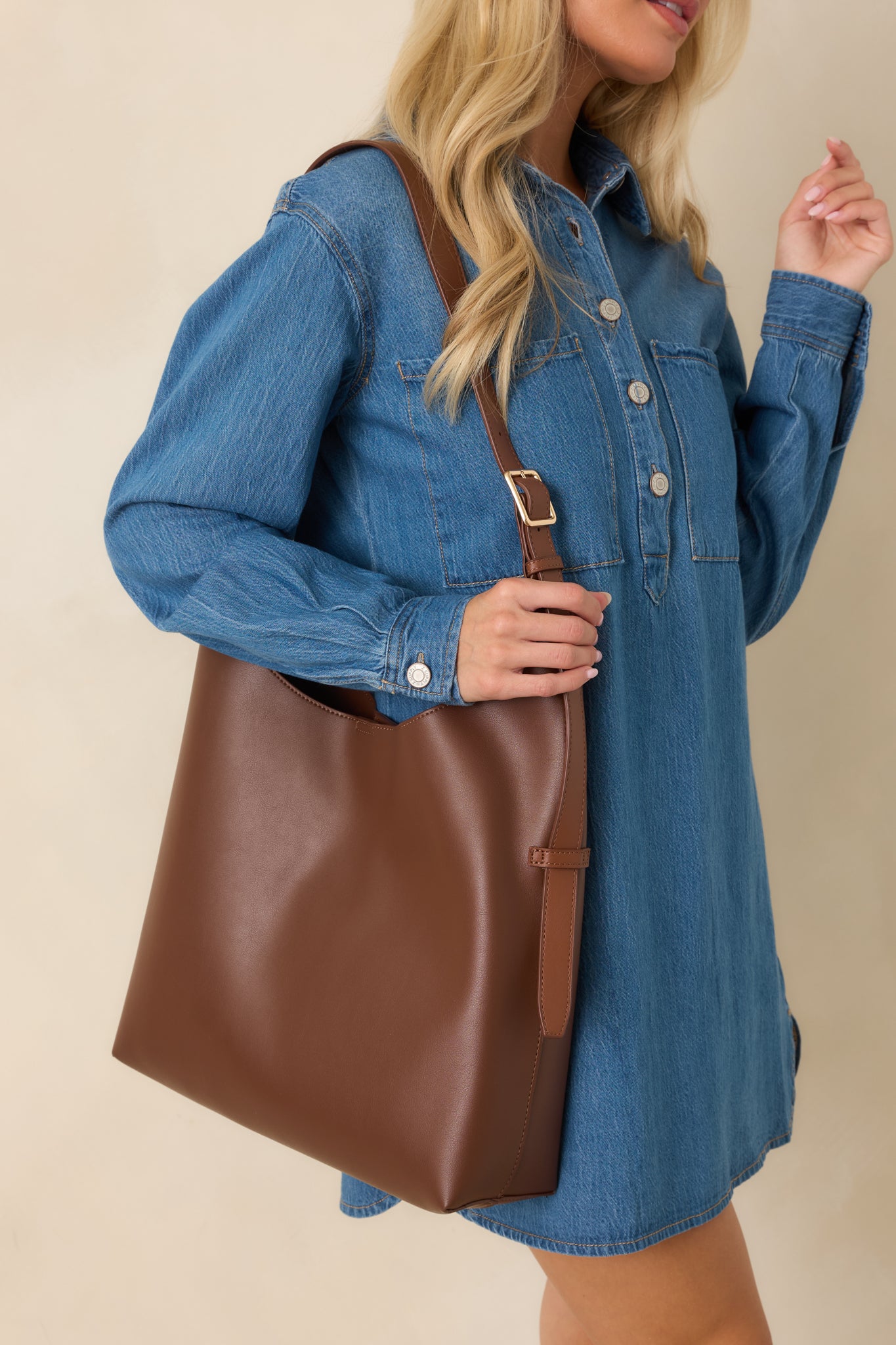 Close-up of a women's chocolate brown faux leather hobo shoulder bag with an adjustable buckle strap and minimalist design.