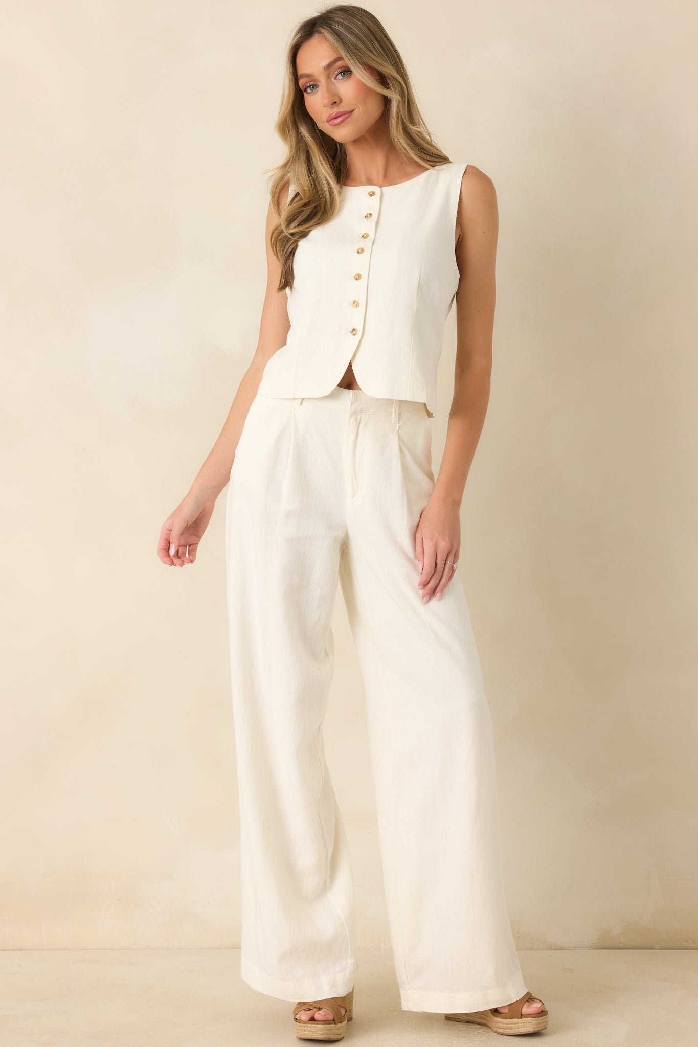 Ivory tailored vest with a sleeveless cut, structured seams, rounded neckline, and elegant minimalist design.
