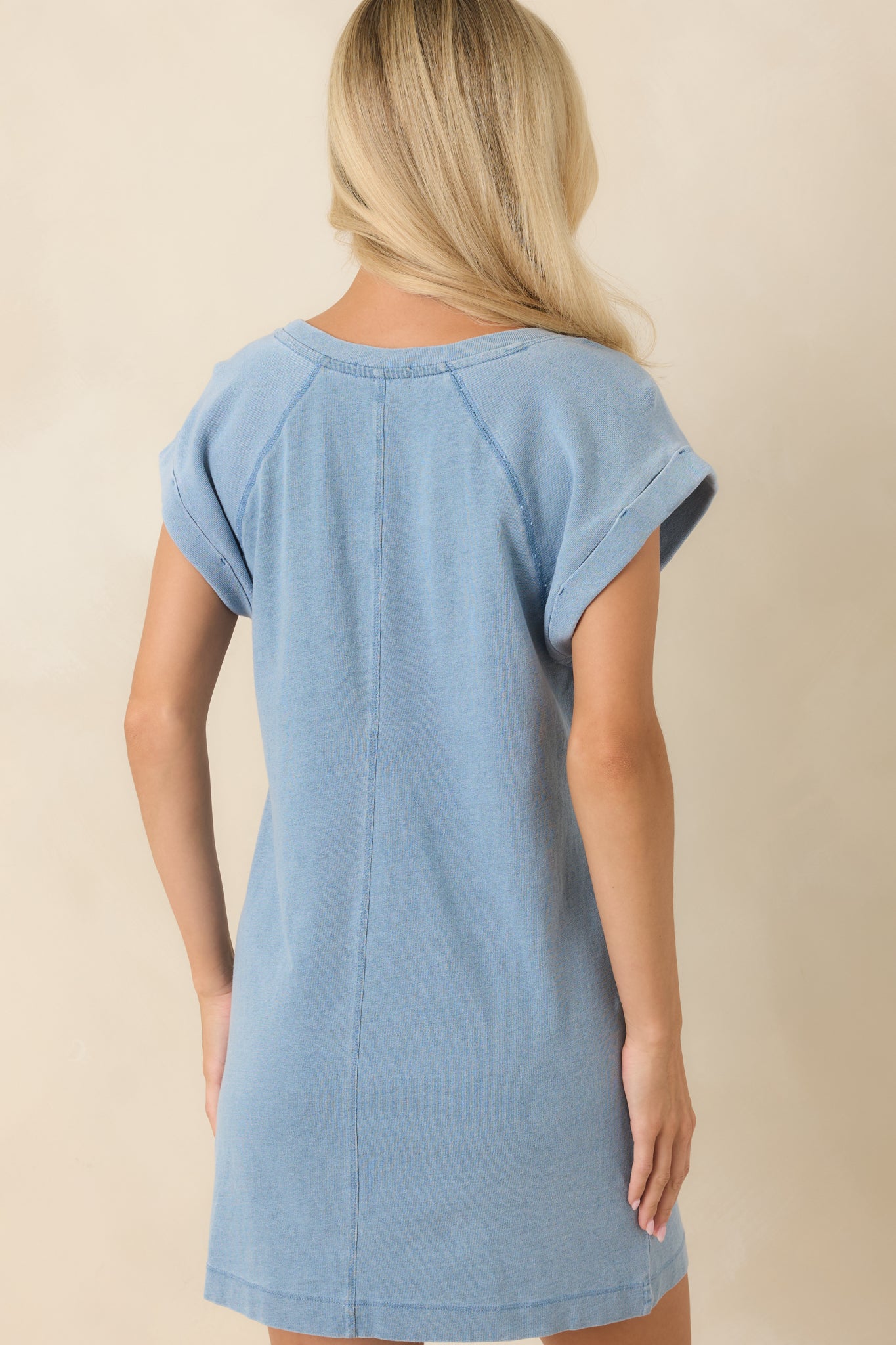 Back view of a women's light blue cap sleeve knit mini dress featuring a relaxed fit, crew neckline, rolled sleeves, and soft lightweight fabric.