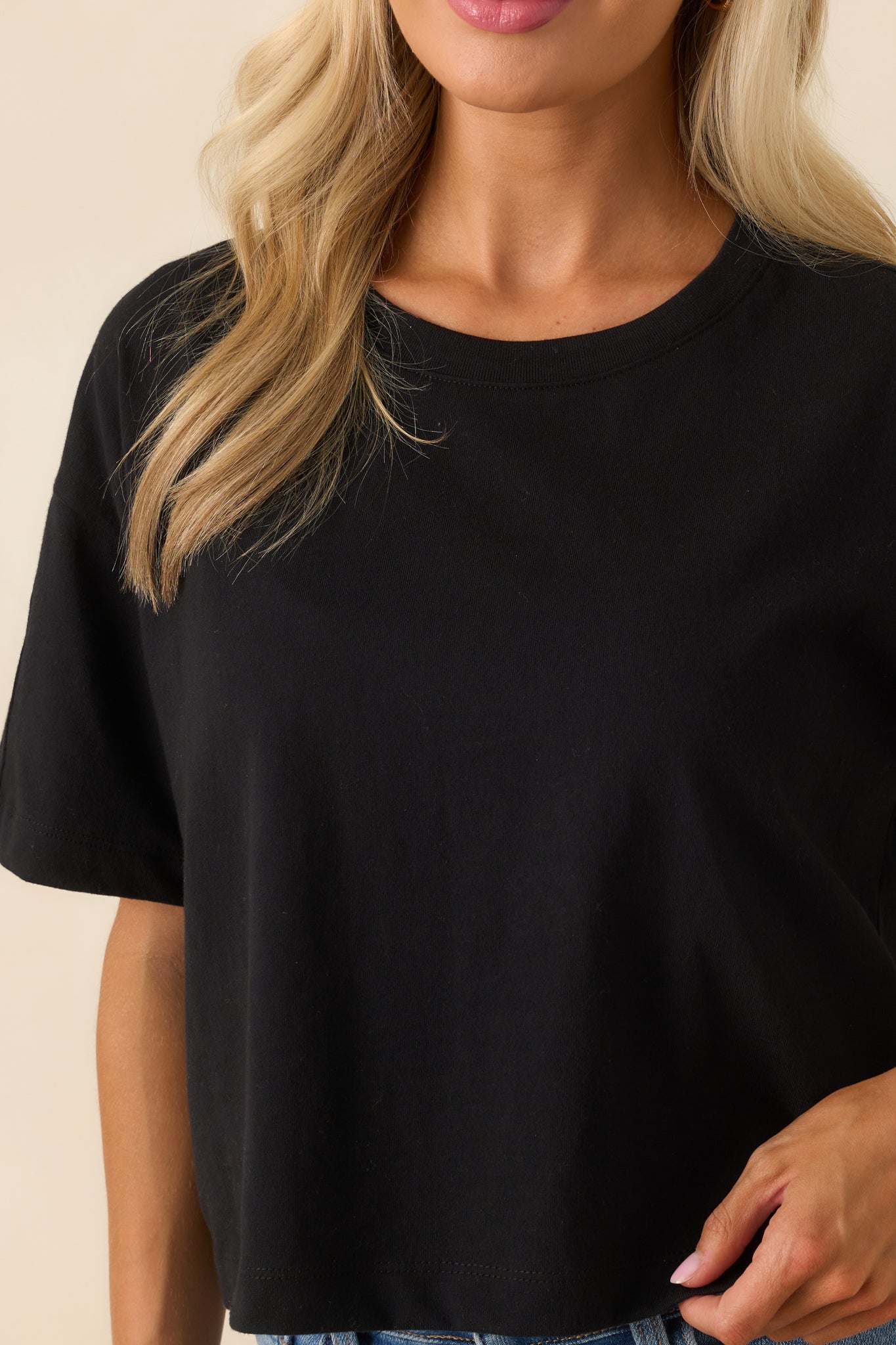 Close-up of the black tee’s cotton fabric texture and ribbed crew neckline.