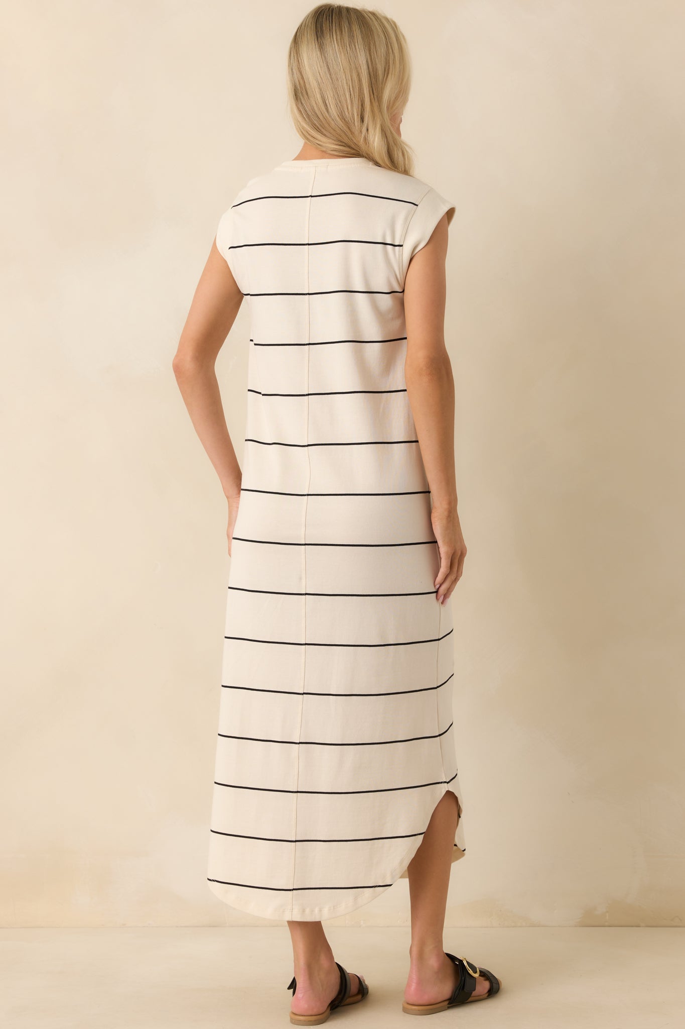 Rear view of the ivory midi dress highlighting the center back seam detail, cap sleeves, and scoop hemline from behind.