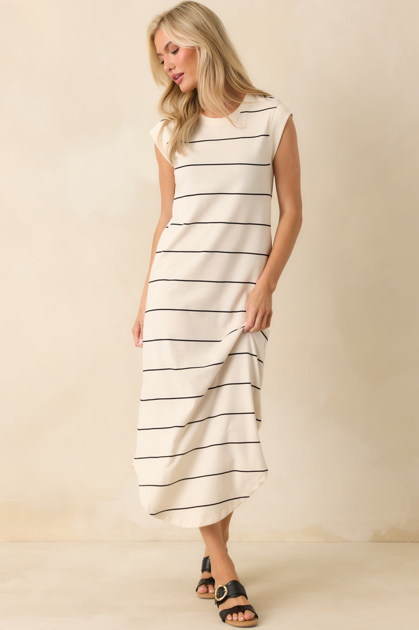 Slight angled front view highlighting the relaxed fit and scoop bottom hem of the ivory pinstripe dress.
