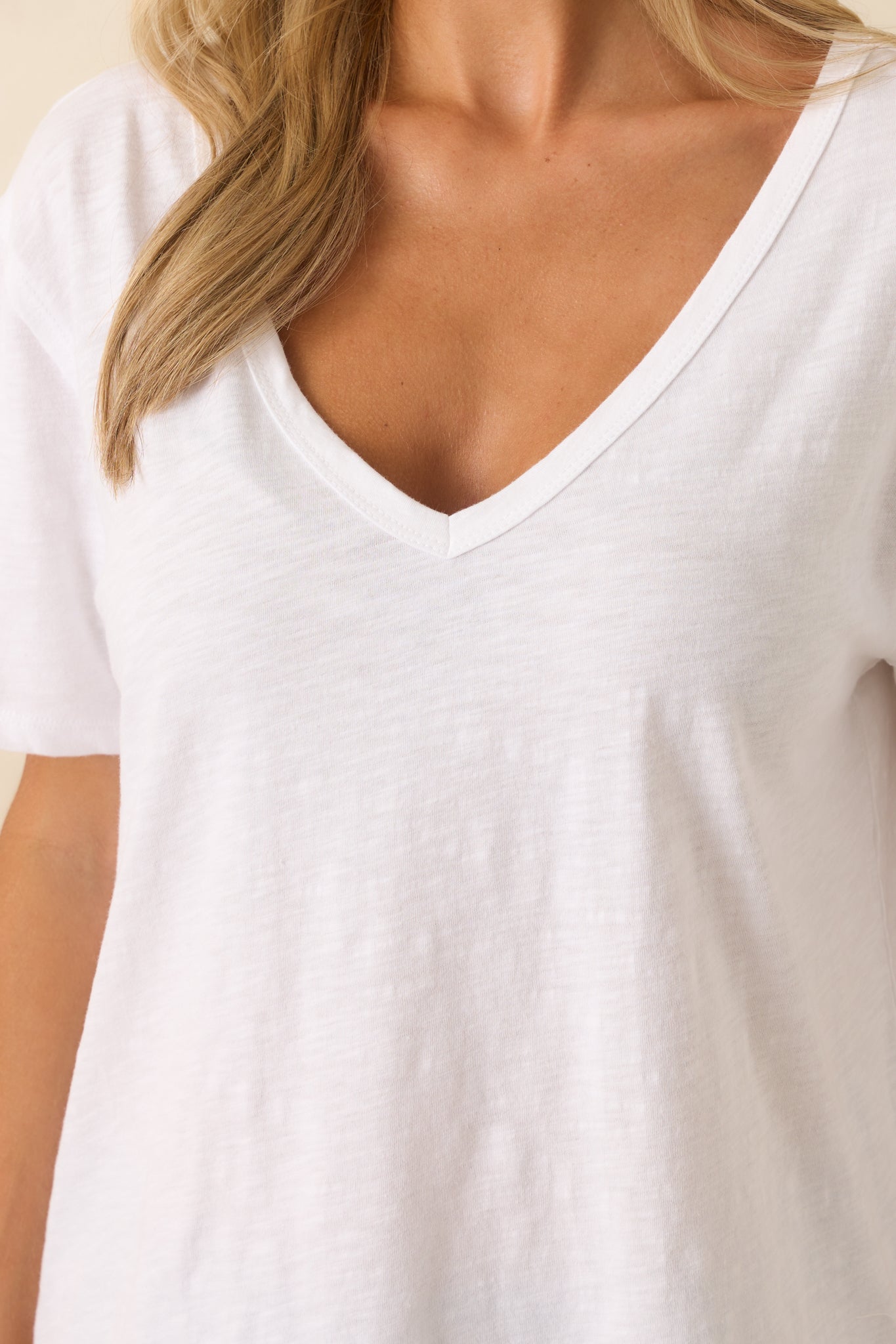 A close-up detail of the v-neckline and subtle texture of the white cotton.