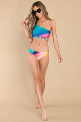 Full body view of this bathing suit top that features a one shoulder neckline with no padding, and adjustable strap, and a colorful additional strap detail under the bustline.