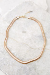 Overhead view of necklace that features a thick, solid gold chain necklace with a lobster clasp. 