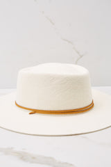 Side view of  this hat that features a round telescope crown with a flat brim and a leather chinstrap around the crown.