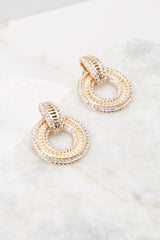 Detailed marble shot of earrings that feature dangle hoops, gold hardware with rhinestone encrusting, and post secure backing.